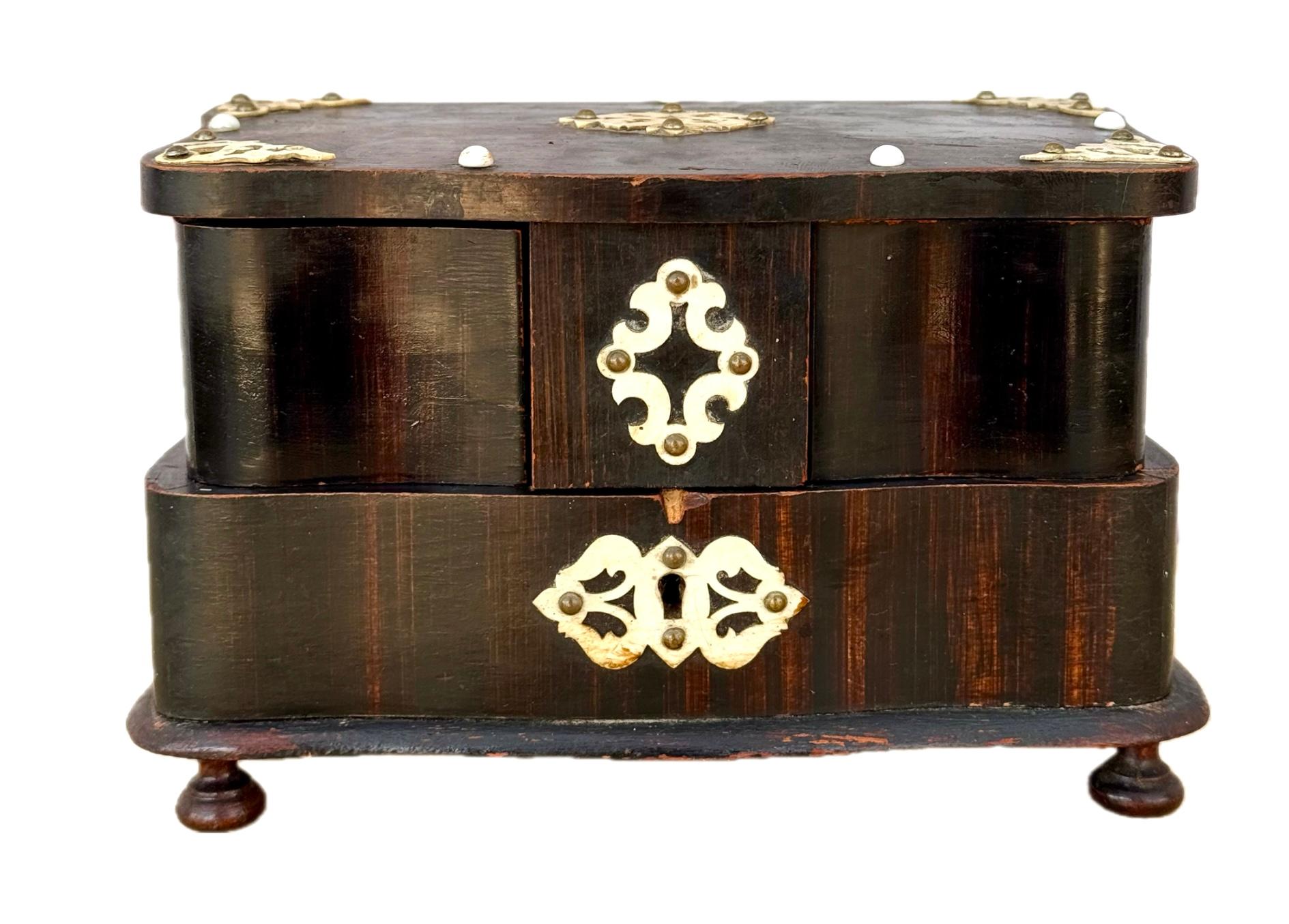 Cofre para joyas victoriano francés del siglo XIX. El ataúd es de madera oscura con adornos de color crema. Tiene una parte superior elevable con dos cajones basculantes sobre el compartimento inferior. La parte superior interior tiene un tejido de