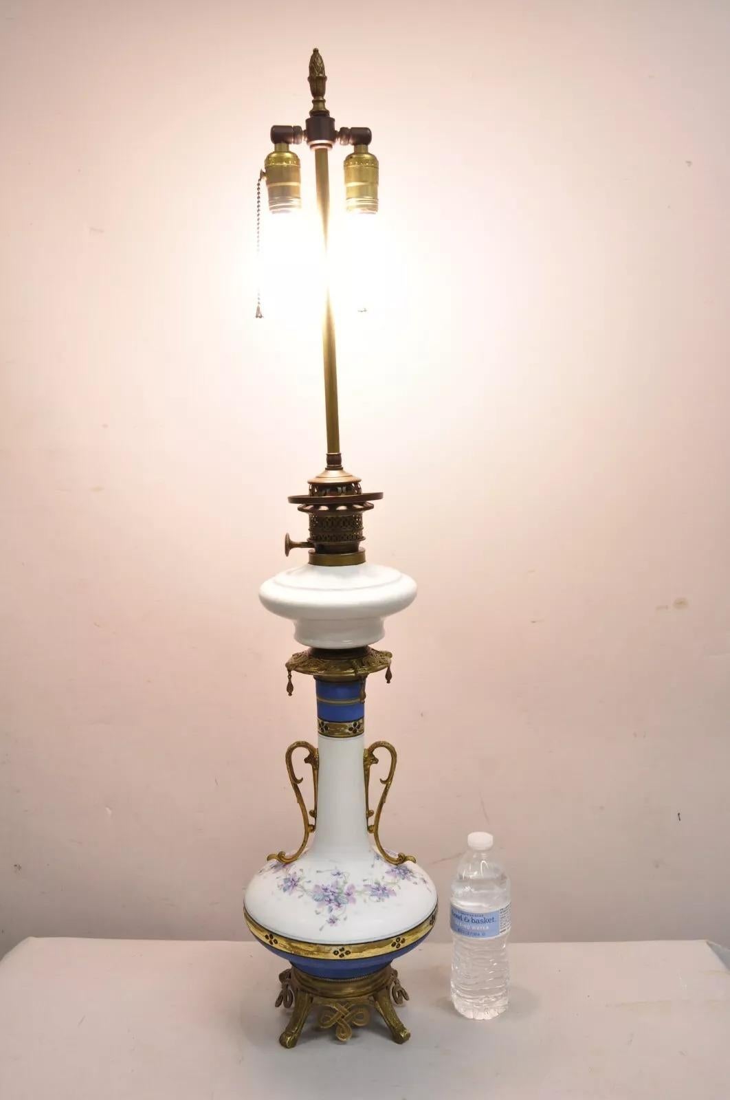Antique French Victorian Hand Painted Porcelain White and Blue Tall German Oil Lamp Converted Table Lamps with Brass Mounts - a Pair. Circa Early 20th Century. Measurements: 40