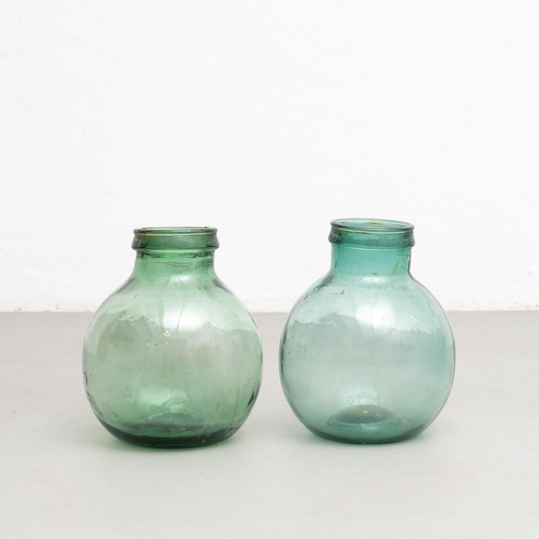 Un set di due antiche bottiglie di vetro Demijohn provenienti da Barcellona.    Realizzato da un produttore sconosciuto in Spagna, intorno al 1950.    In condizioni originali, con lievi usure dovute all'età e all'uso, conserva una bella patina.   