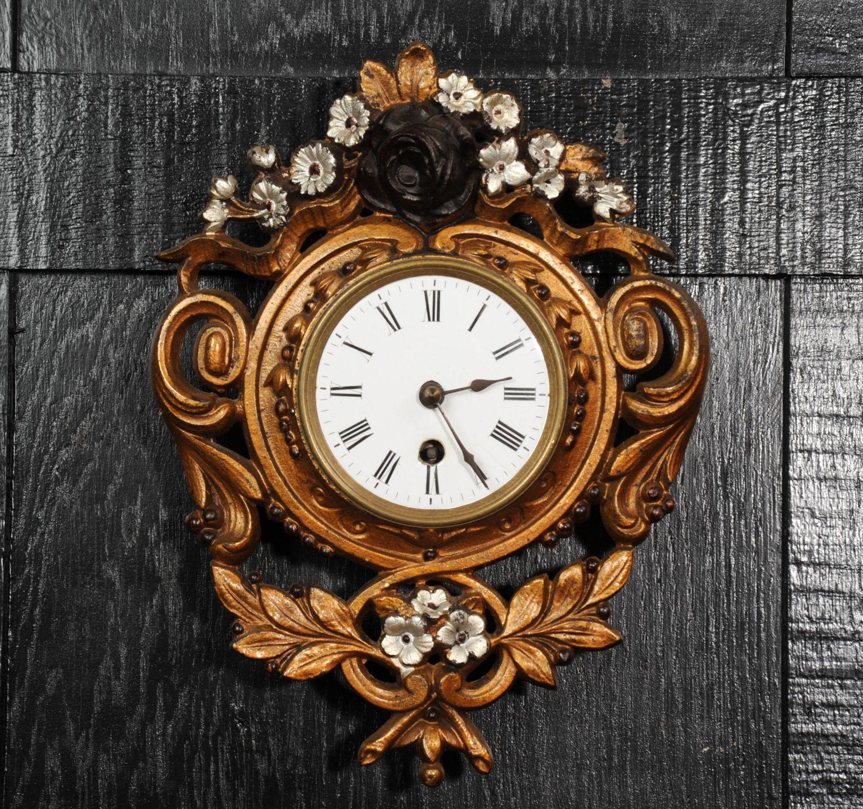 A charming antique French wall clock by the famous maker Japy Freres. Beautifully modelled with leafy scrolls and flowers and painted with gold lacquer with the flowers picked out in silver and black. The lacquer has mellowed and faded beautifully