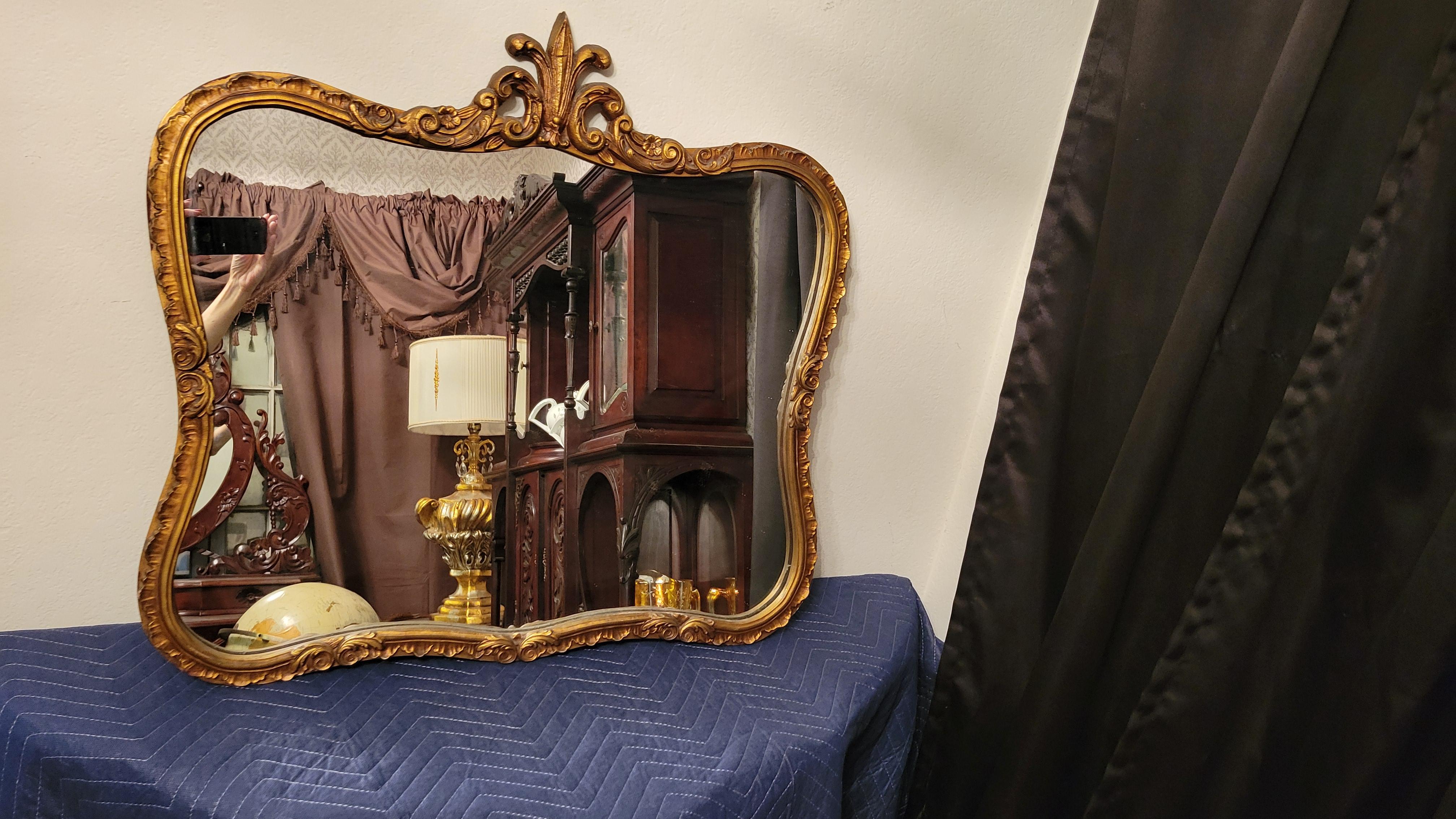 Miroir mural ancien en forme de serpentin dans un cadre en bois sculpté avec un motif de Fleur de Lis.
Le cadre mesure 29,5