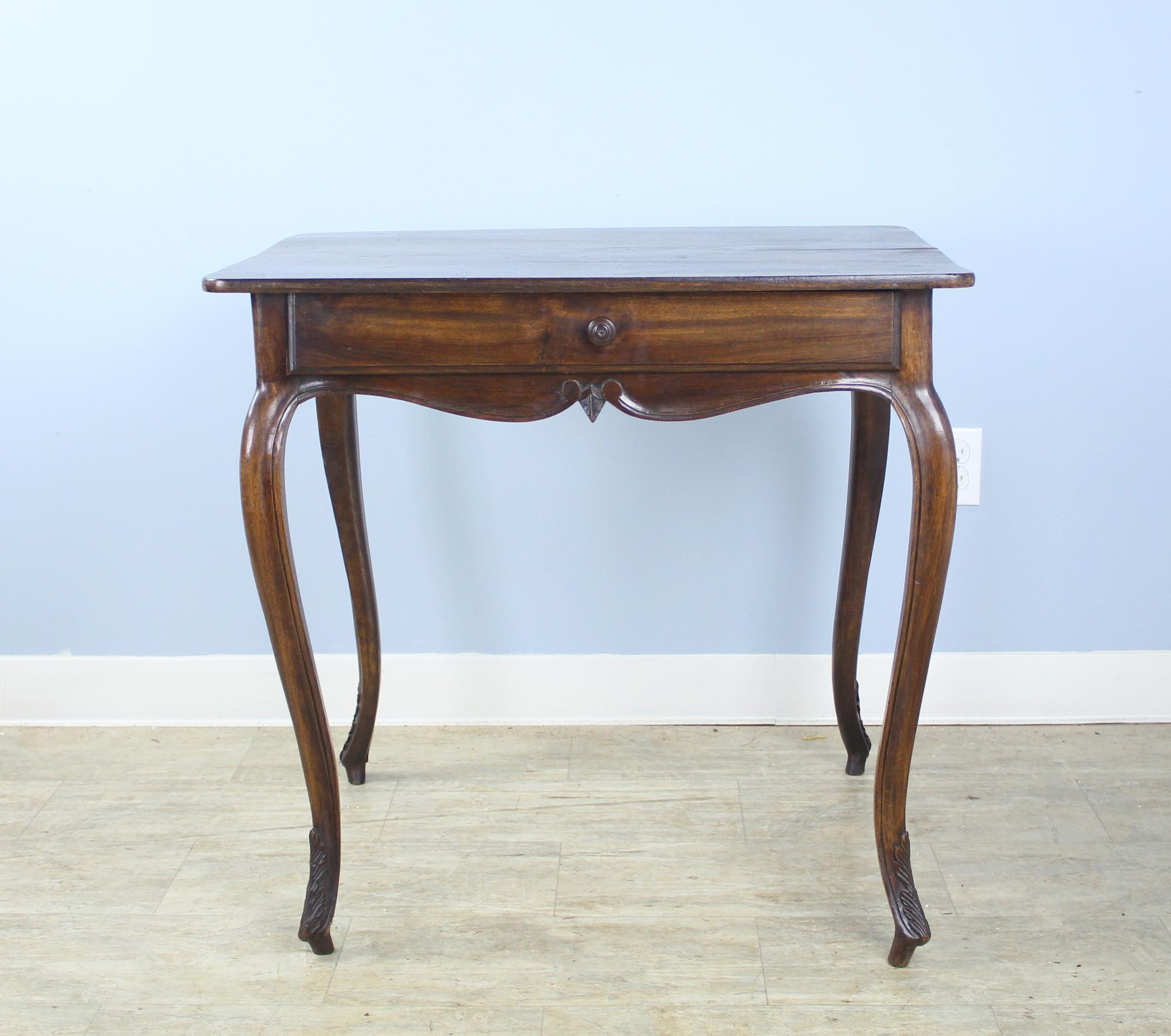 A graceful dark walnut side table with cabriole legs and articulated carved feet. We love the quirky offset knob on the drawer.