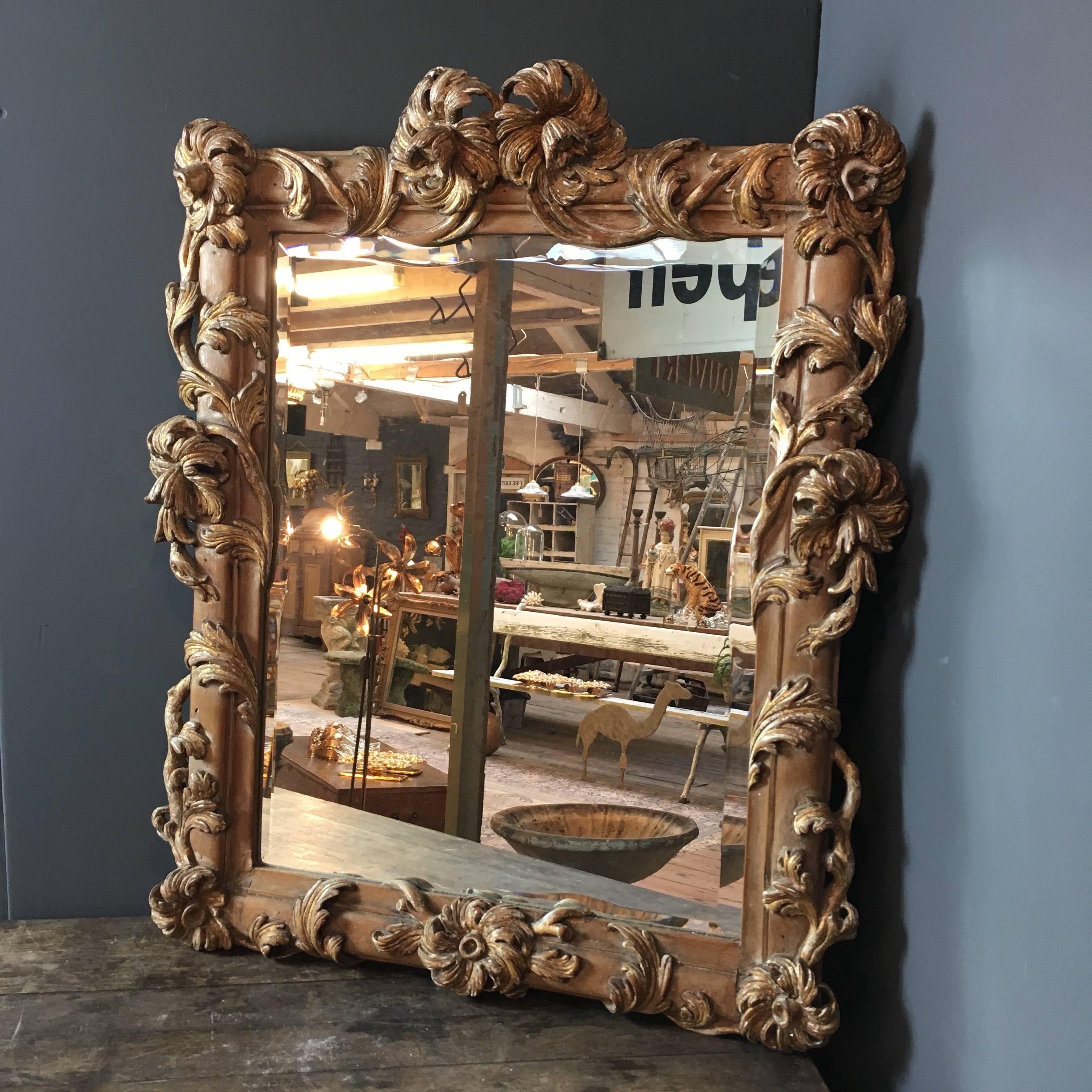 Antique wooden carved French mirror 
The mirror has its original glass which is hand bevelled 1 inch width, the bevel follows the lines of the carved frame
The wooden carvings of large flowers and leaves surround the frame, they have a beautiful