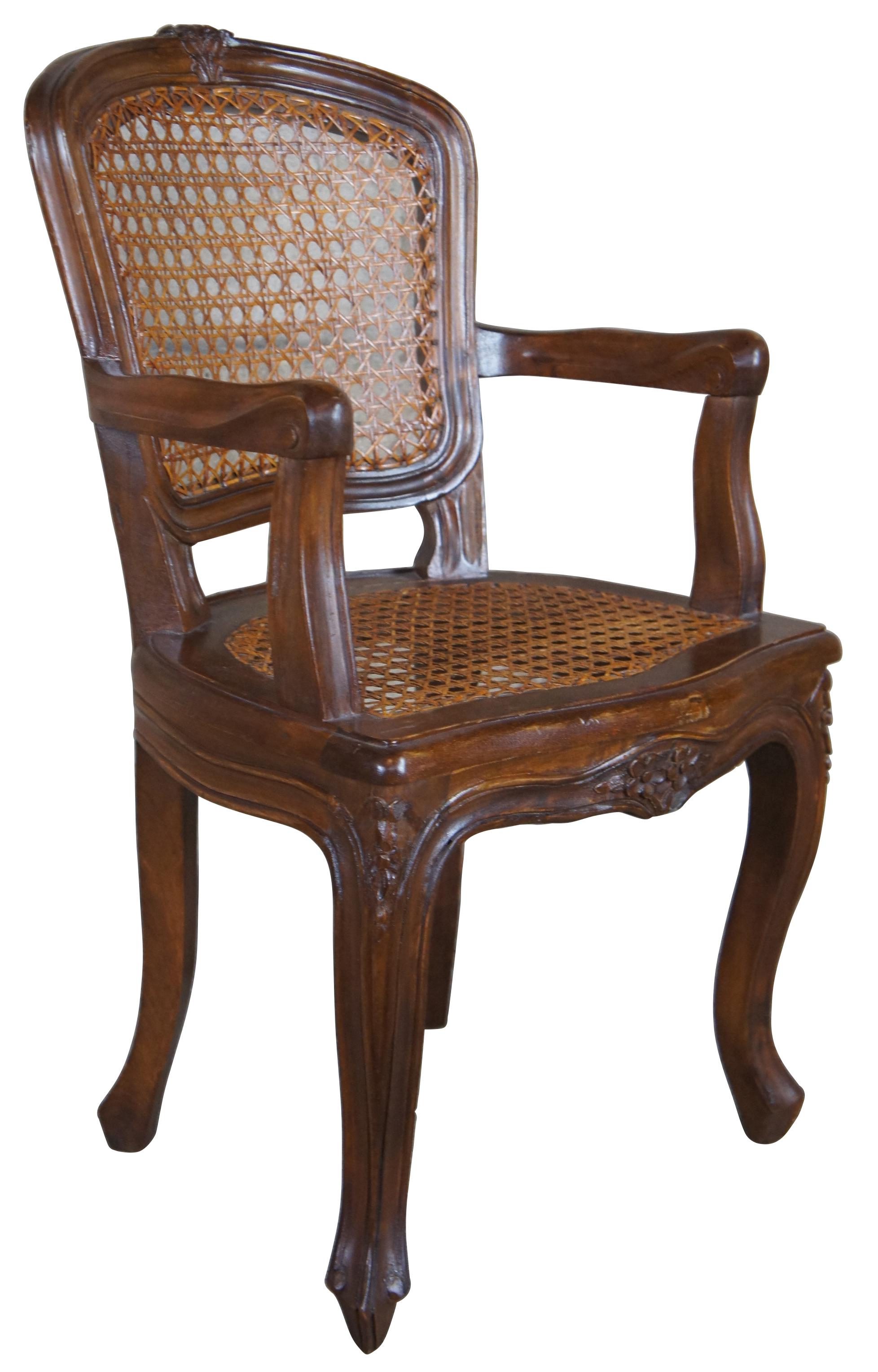 Exquisite antique child or doll size French arm chair. Made from walnut with meticulous detail. Features carved floral embelishments, cabriole legs, hand cane seat and back. Measure: 25