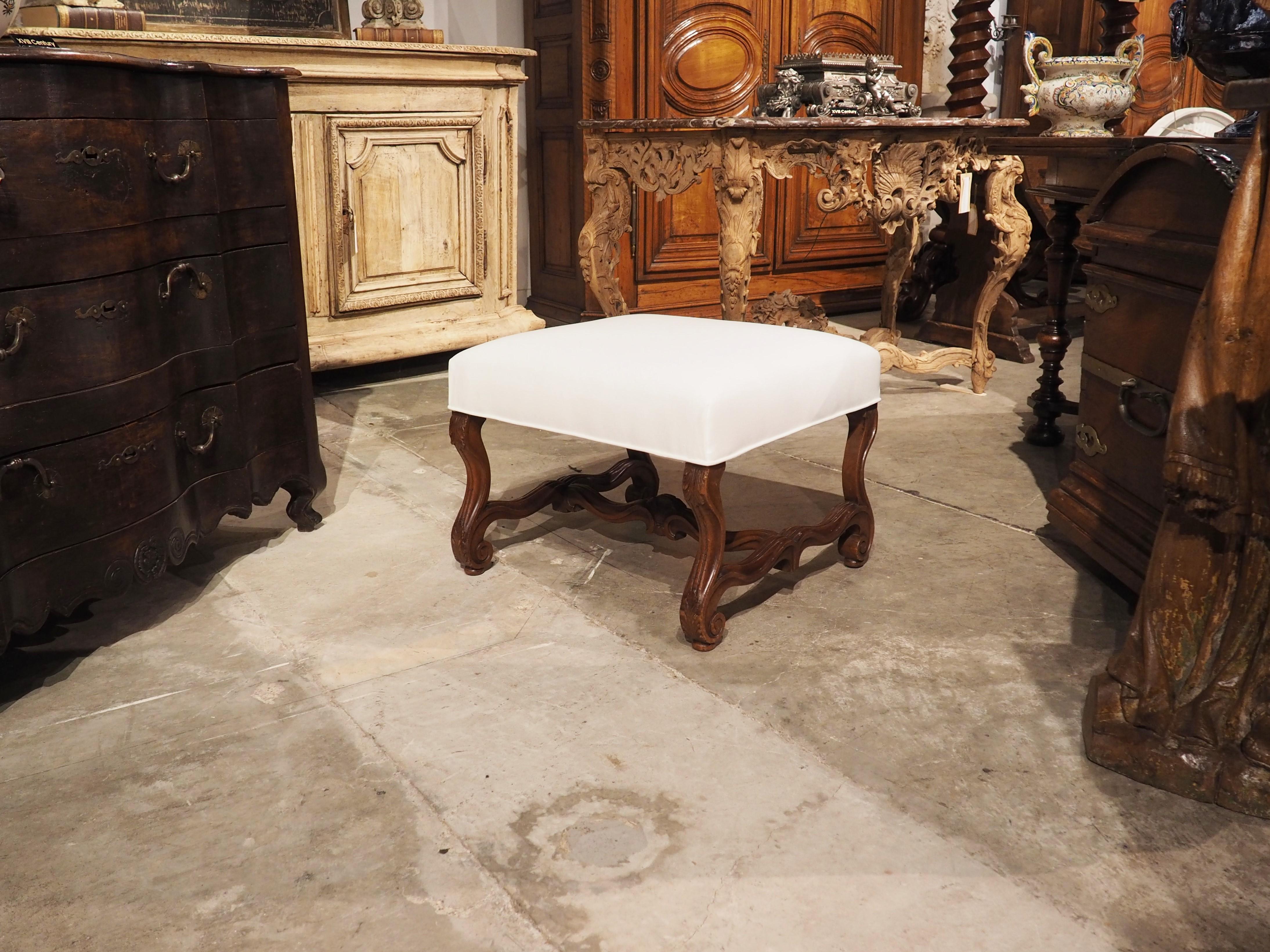 Hand-carved in walnut in France during the early 1900’s, this tabouret stool features os de mouton legs and stretcher. The very distinct shape of os de mouton furniture make it a popular addition for most interior design styles, as the subtle