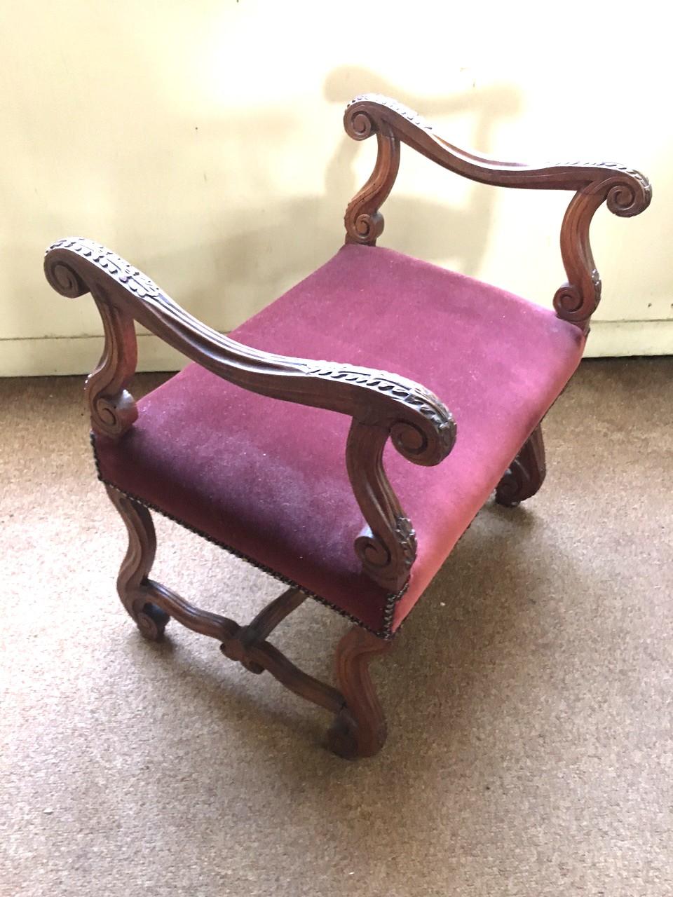 Ce beau banc en noyer français présente des accoudoirs curvilignes avec des feuilles d'acanthe sculptées et est soutenu par un piétement en serpentin sculpté. Le siège est un joli velours couleur bordeaux relié par des agrafes en laiton tout autour. 