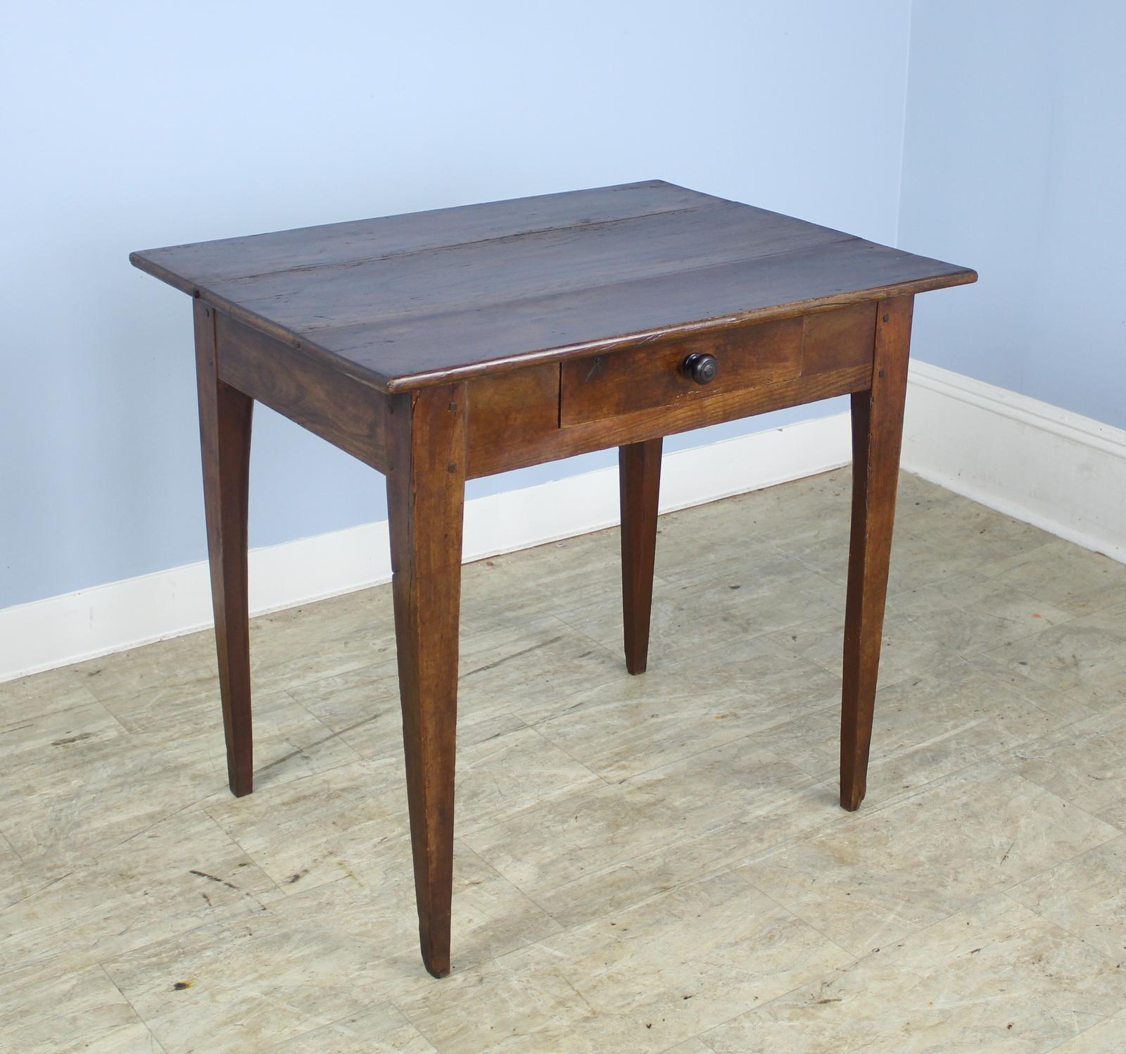 A handsome side table in rich walnut with classic tapered legs and a single drawer. The top has some interesting old wear, shown. Grain and patina are very nice.