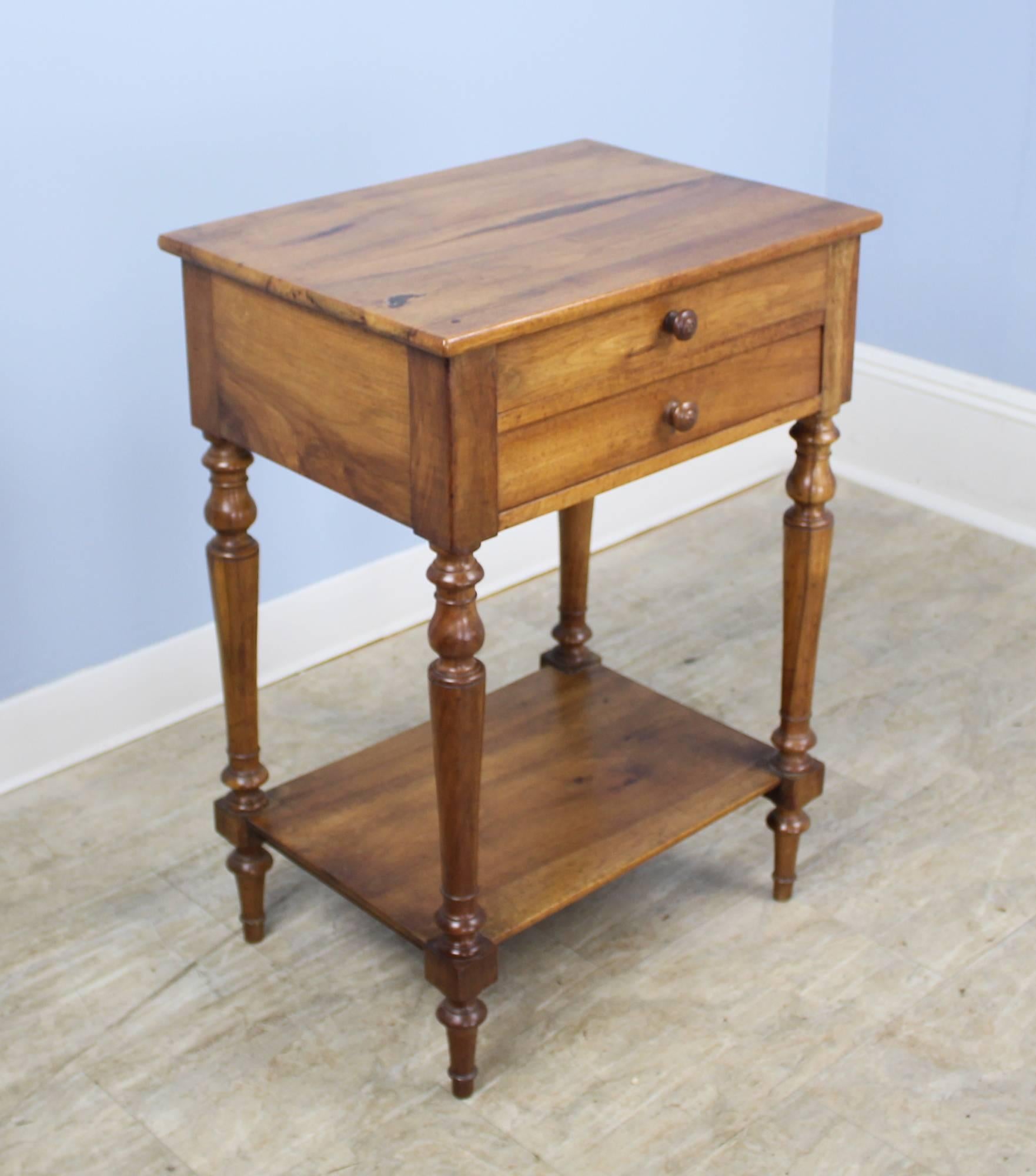 A splendid walnut side table with double drawers and graceful turned legs. Wonderful walnut grain and color and good patina. The lower shelf adds a note of utility.