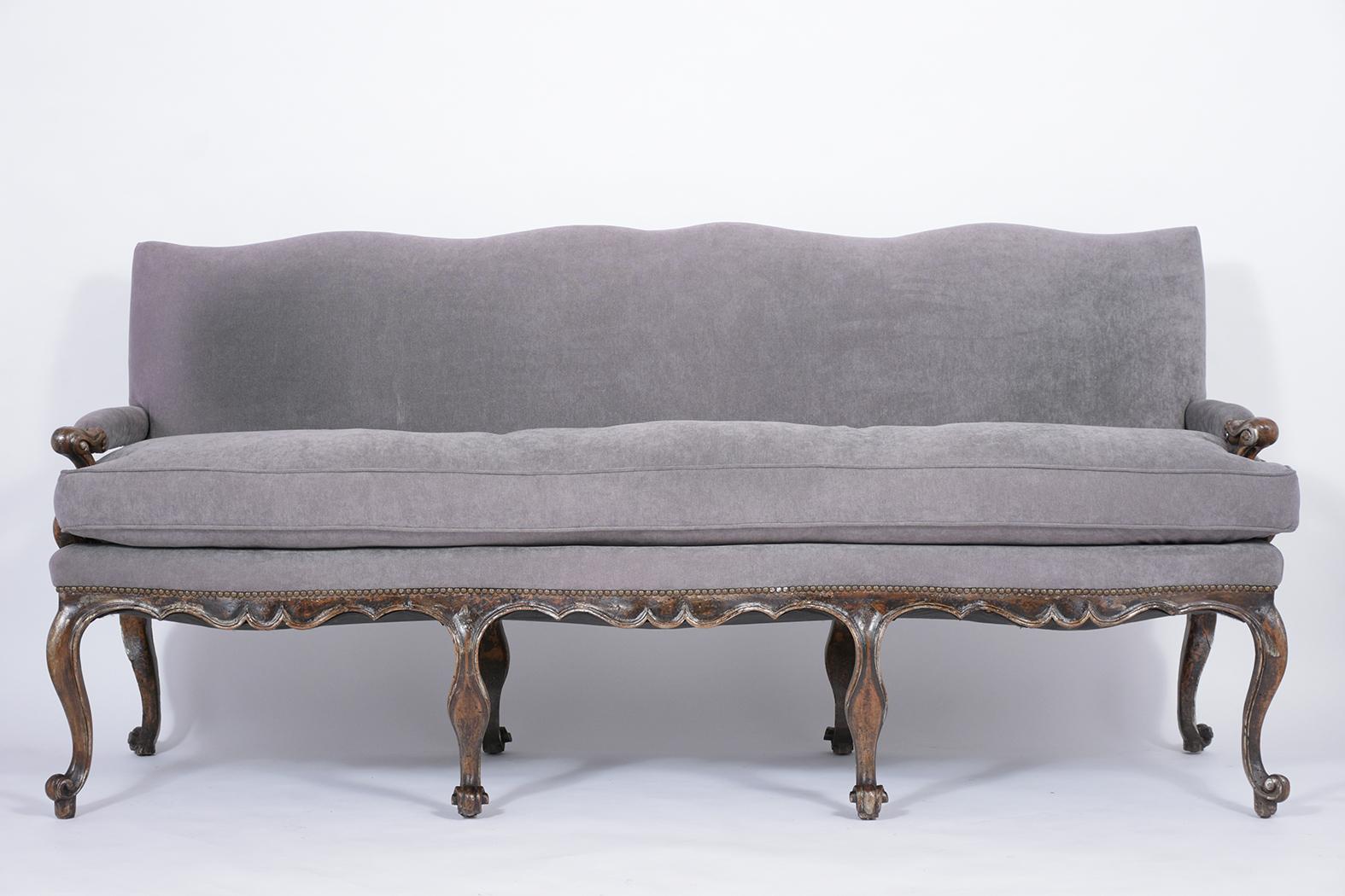 An extraordinary 18th-century Louis XV walnut sofa made out of walnut wood with hand-carved details throughout and features the original walnut color with silver-gilt details and a beautiful patina finish. The sofa has been professionally