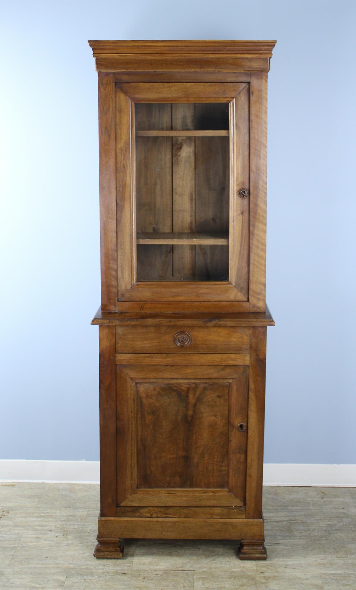 An elegant antique walnut vitrine or cupboard, suitable for a variety of purposes and rooms. The walnut has marvelous color and good patina. The top has two adjustable shelves and the hand carved walnut escutcheon closes snugly with the key. Below