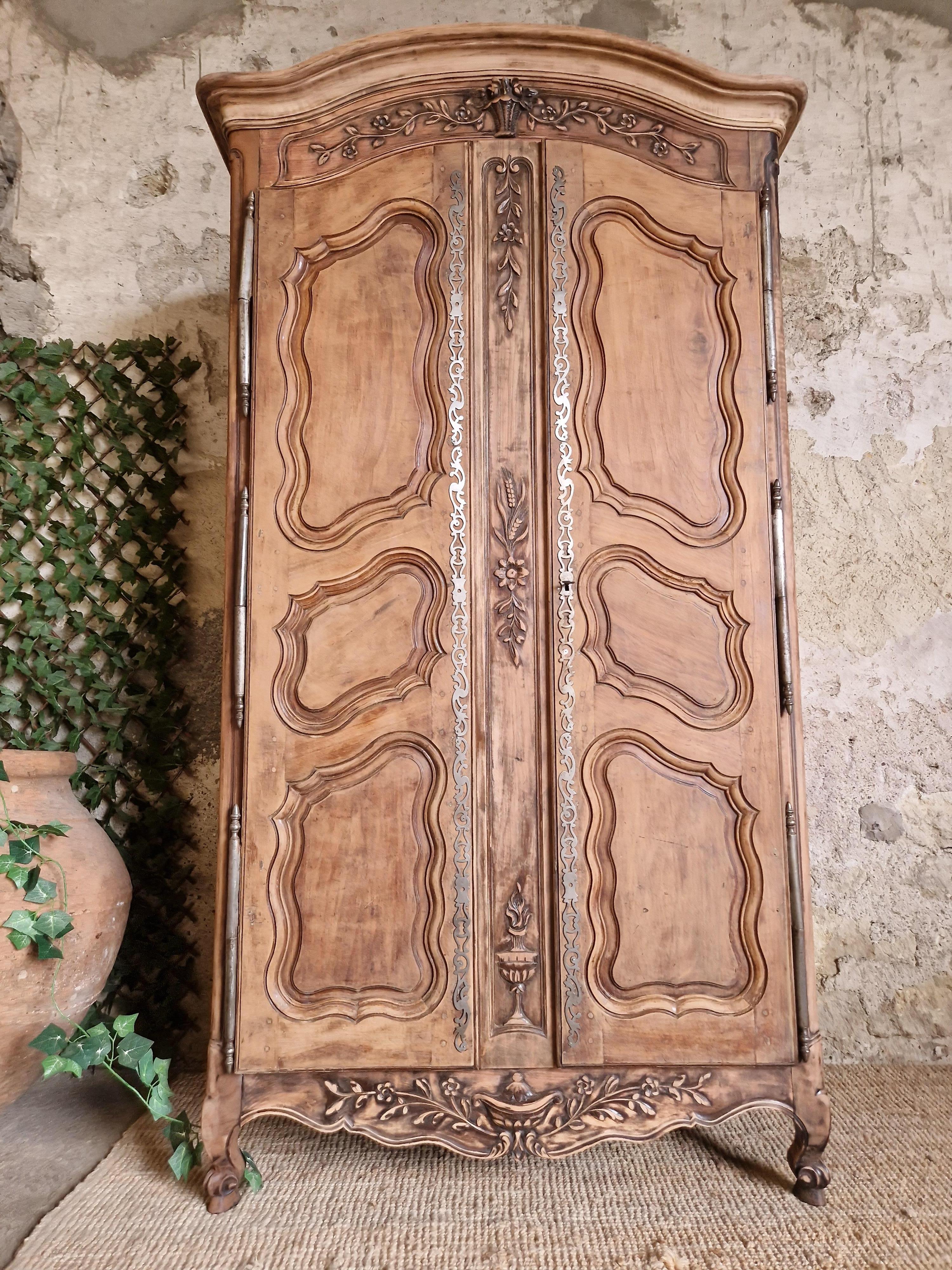 This beautiful freestanding wardrobe from the 19th century is crafted from solid wood. This antique piece features carvings, iron work decorative plaques with a working lock. The solid wood finish has been stripped back give it a rustic look that