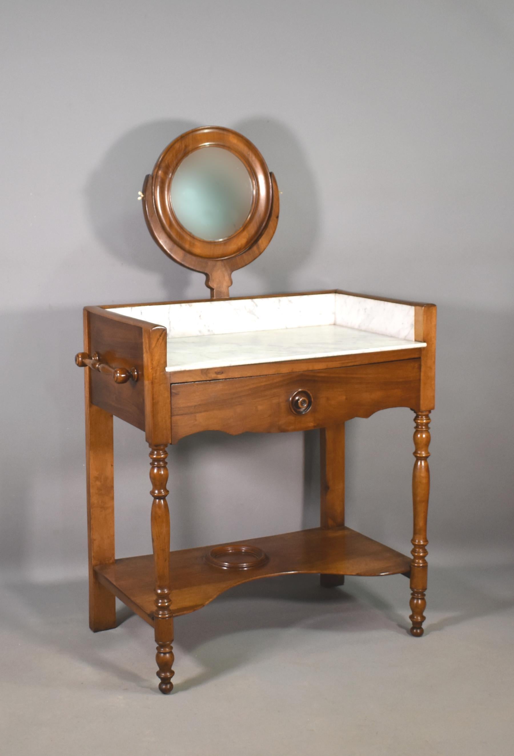 This lovely French Walnut Washstand is in great original condition and features a good-sized round mirror within a solid walnut frame with moulded inner and outer edges.

The mirror is held in a lyre support with brass wingnut adjusters.

The