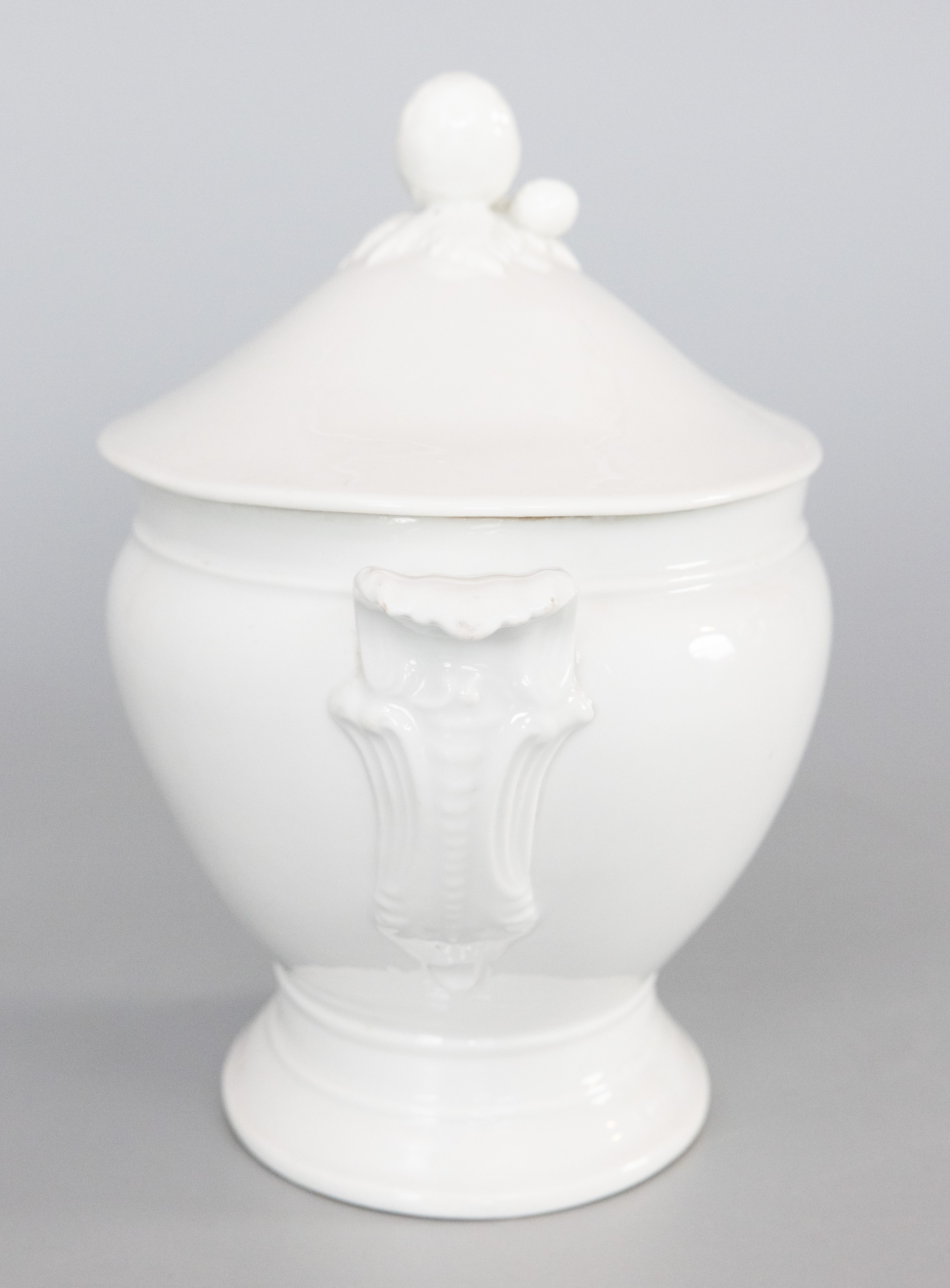 A gorgeous large antique French white ironstone porcelain lidded soup tureen soupière, circa 1900. No maker's mark. This fine soup tureen has a large oval design, decorative acorn finial, and lovely ornate scrolling leaf handles. It displays