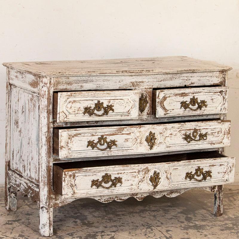 The distressed white paint adds a romantic feel to this oak chest of drawers. While the paint was added later, the carved panel drawers and scalloped skirt are gently accented by the paint as well. Expected age-related separation of wood is seen in