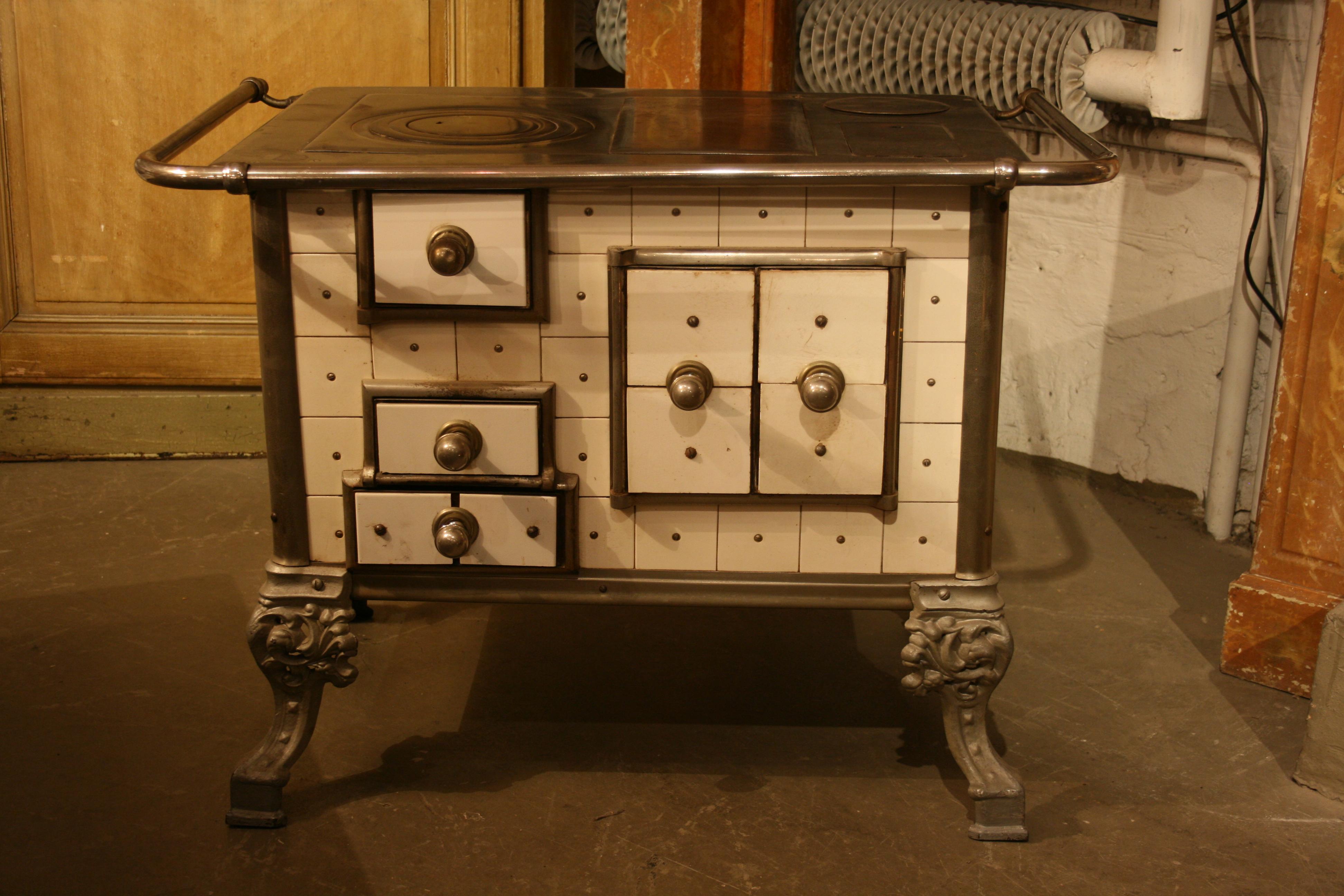 Original old French stove from circa 1900 with white tiles and round cast-iron combustion chamber insert, as well as 4 cast-iron feet. The trigger is in the back right. The firing takes place from above. The right-hand doors close the baking chamber