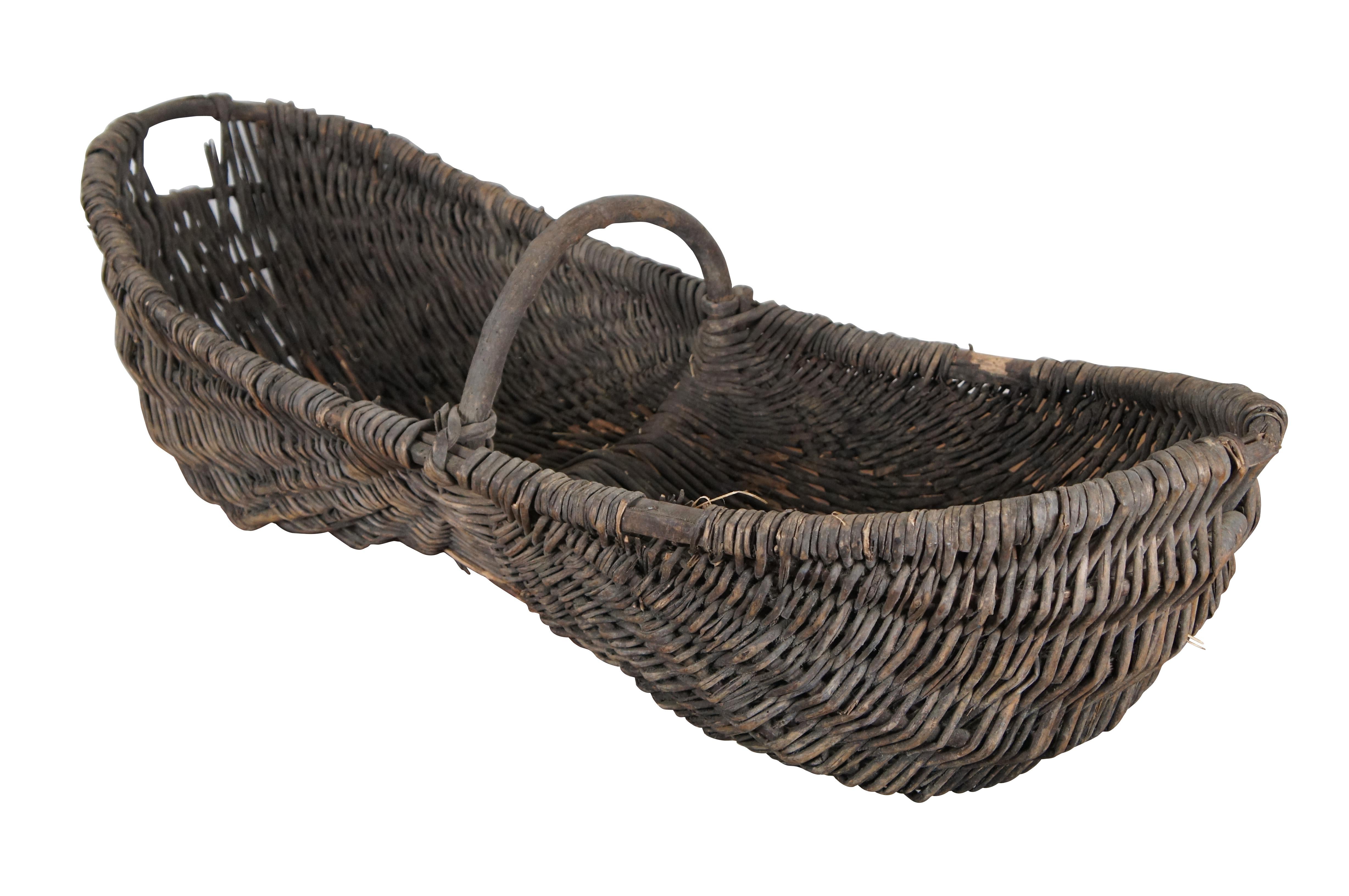 Large and impressive antique grape / wine harvest buttocks basket. Created in the Burgundy region of France circa 19th century, the unique basket made of handwoven wicker is oval in form and features a wooden frame with handle across the top.