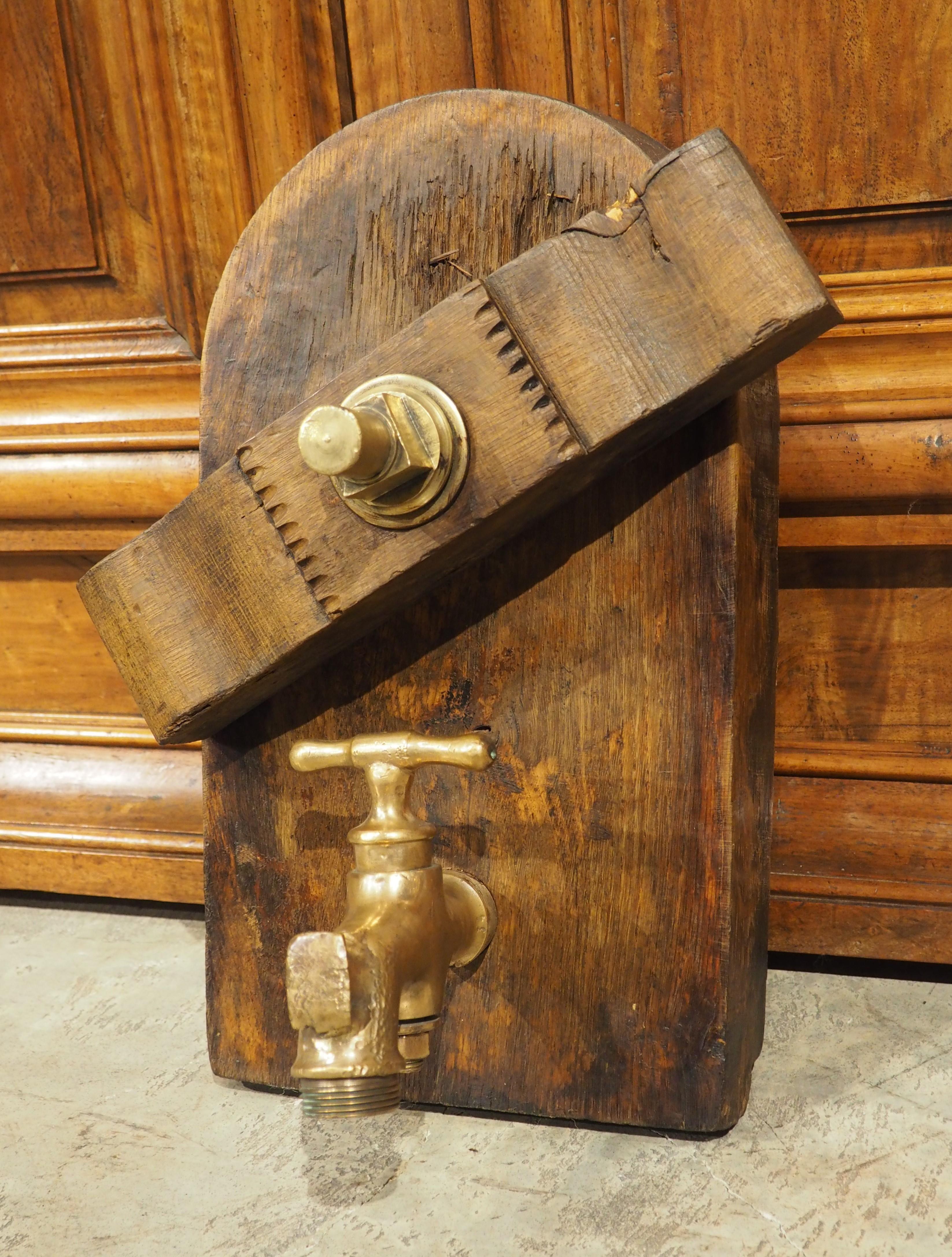 Hand-carved circa 1890 from oak, this arched-shaped piece of wood was originally the access door to a wine cask at a French vineyard. There is a shaped crossbeam near the top that is affixed with a large bronze bolt that was designed to secure the