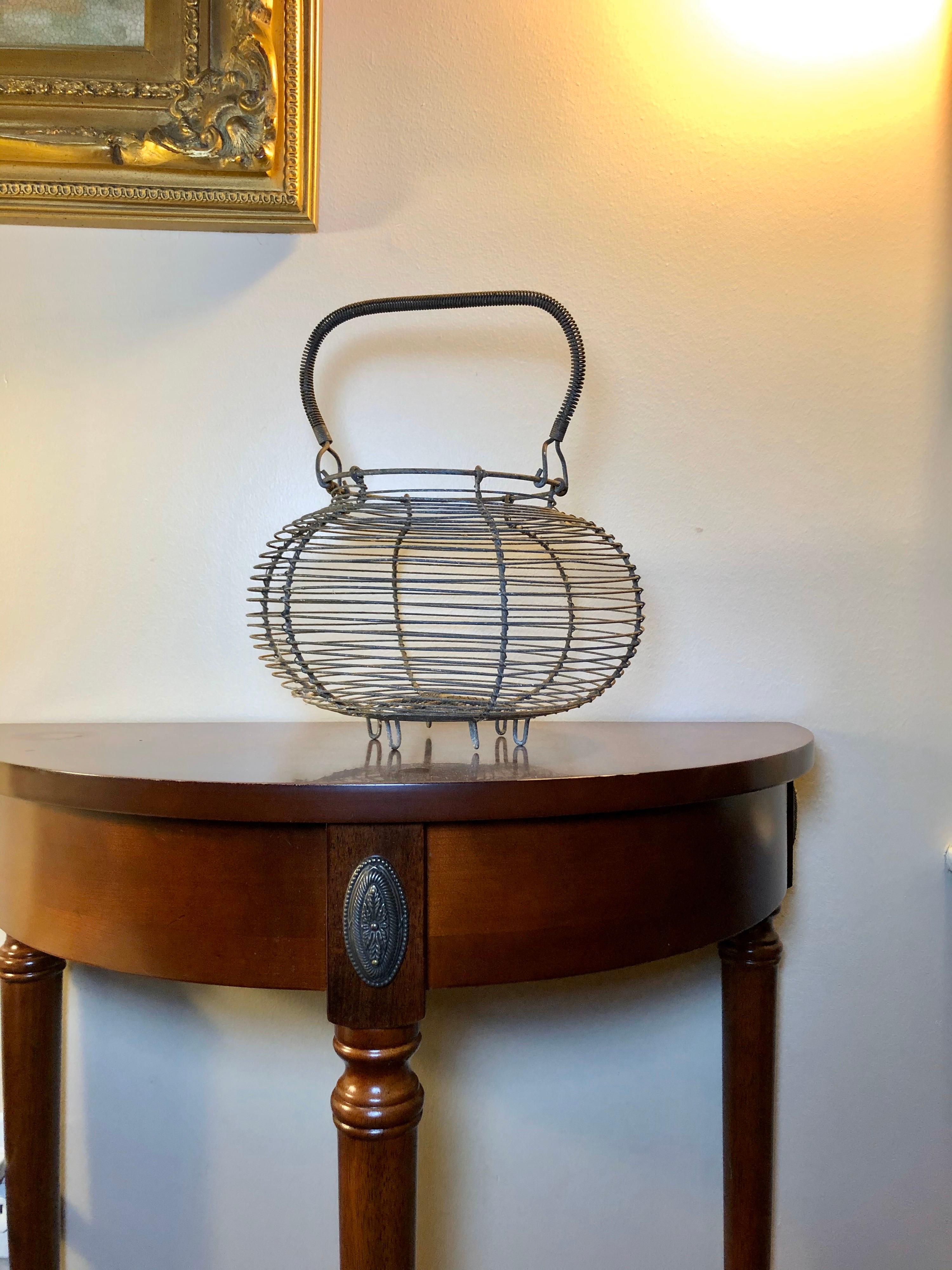 This classic French wire basket was traditionally used for collecting and storing eggs. The bulbous design is very pleasing, and makes an appealing silhouette with the coiled wire handle. Not too big, not too small. The metal is oxidized but strong