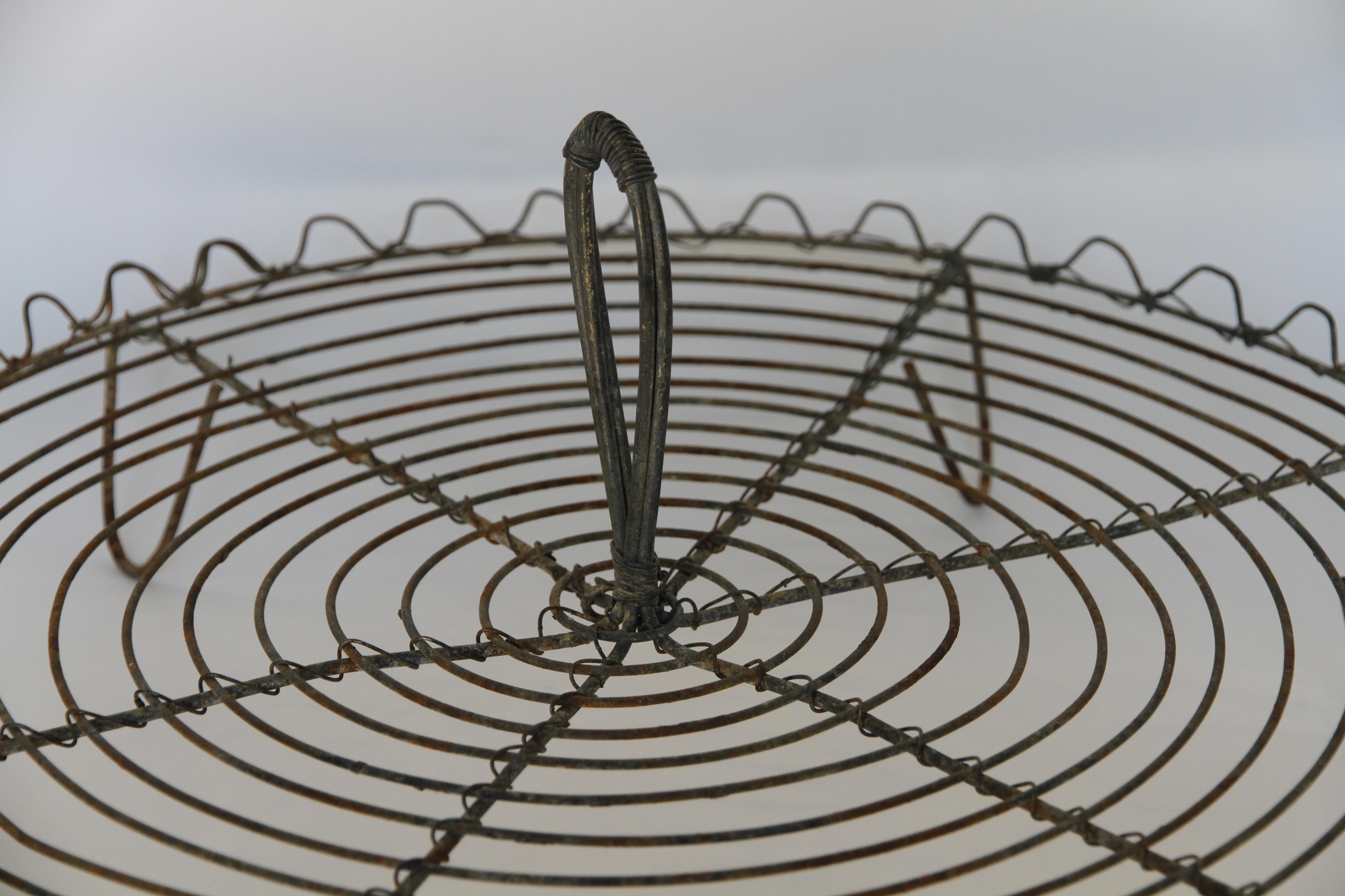 A large antique French wire cooling rack used for cooling pastries and bread straight from the oven. The handle was used to move the rack from kitchen to bakery for display. The tray has beautiful looped wire edging and stands on six wire legs. A