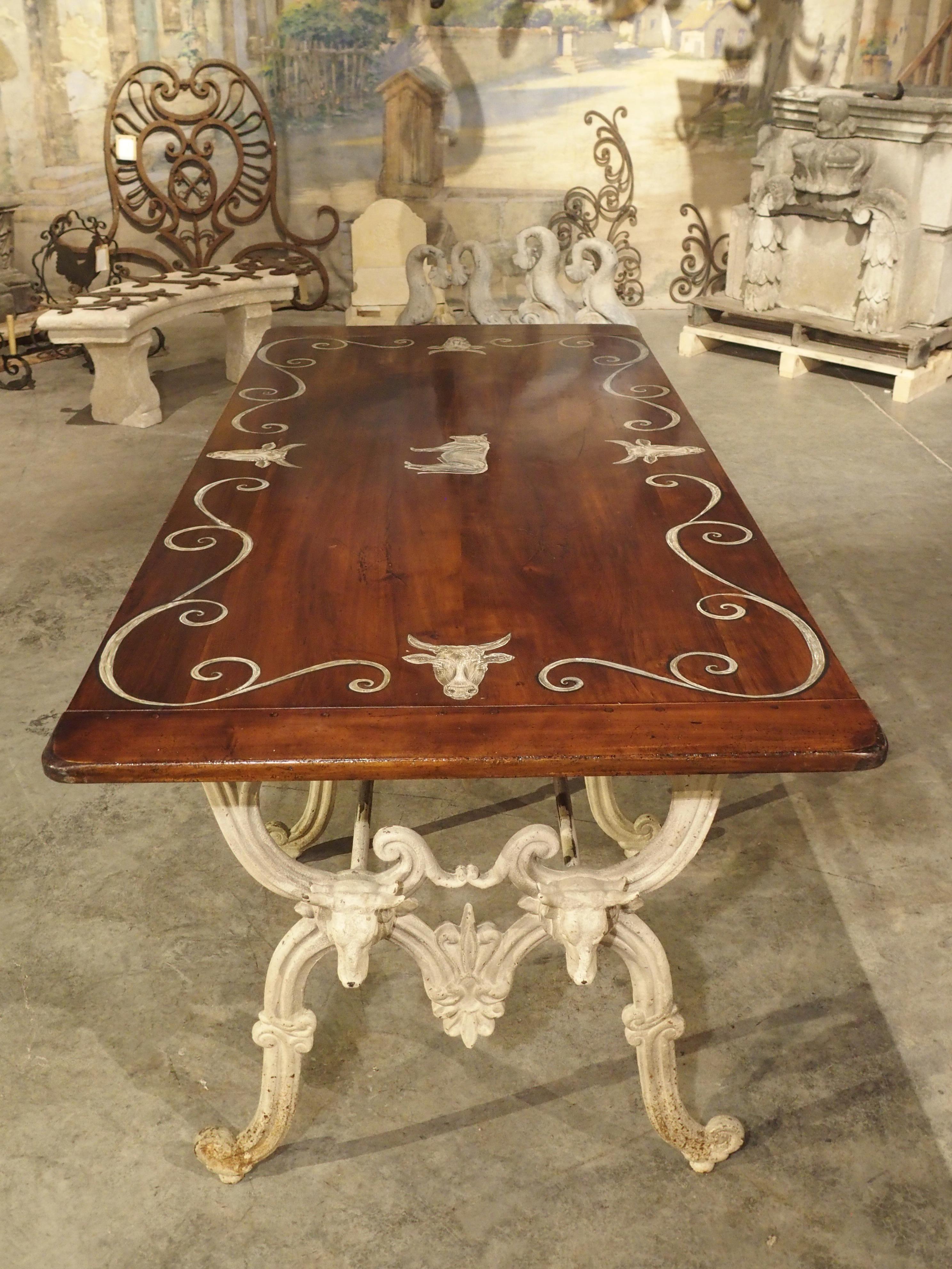 This amazing French table was originally used to display cuts of meat in a butcher shop. Butcher tables had marble tops, but this one has a wonderful wood top with painted bull heads, a big center bull, and scrollwork, all which match the color of
