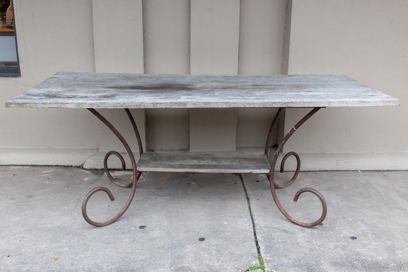 This antique table was sourced from France and came out of a Parisian flower shop. The iron base features wonderful, curved legs with a lower, inset shelf and the distressed finish adds lots of character. The table is weathered and shows some stains