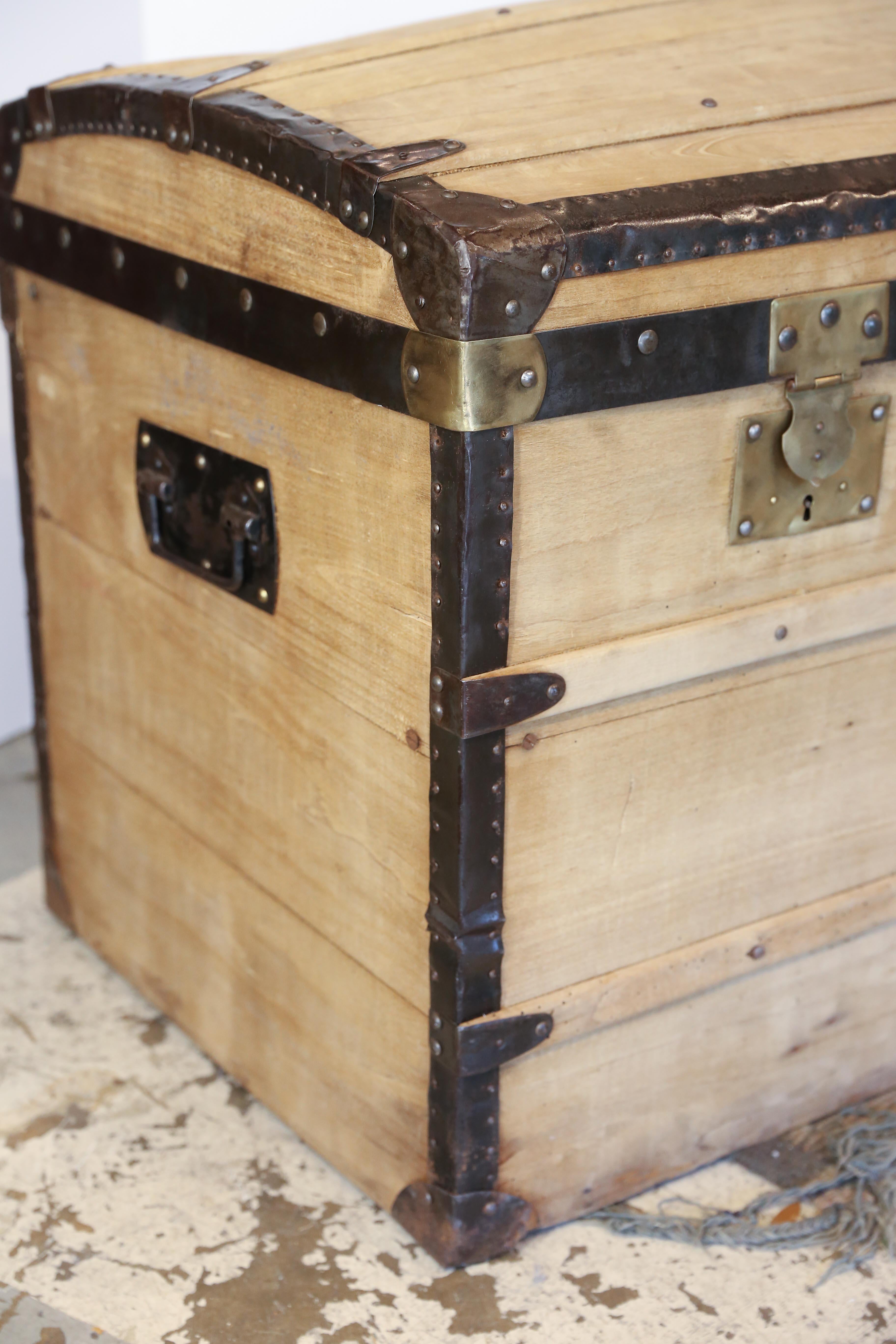 A fantastic, antique wood and iron dome-top trunk perfect for storing all manner of items-- blankets, throw pillows, etc. This piece has been stripped of its original finish, which really highlights the iron frame and brass locks. Handles at the