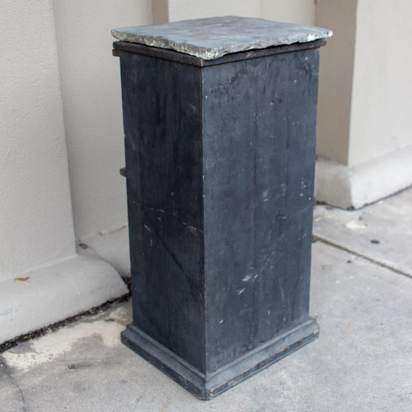 Add a rustic touch of presence with this antique wood pedestal with slate top. This piece is perfect for displaying sculpture, jardinieres, and other decorative elements. The wood base is hollow and open at the bottom, and has a distressed black
