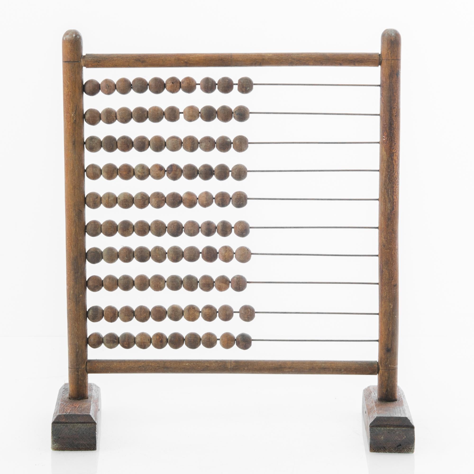 A wood and metal abacus from France circa 1900. This antique counting device captivates with its wayward charm, a curious remembrance from another era.