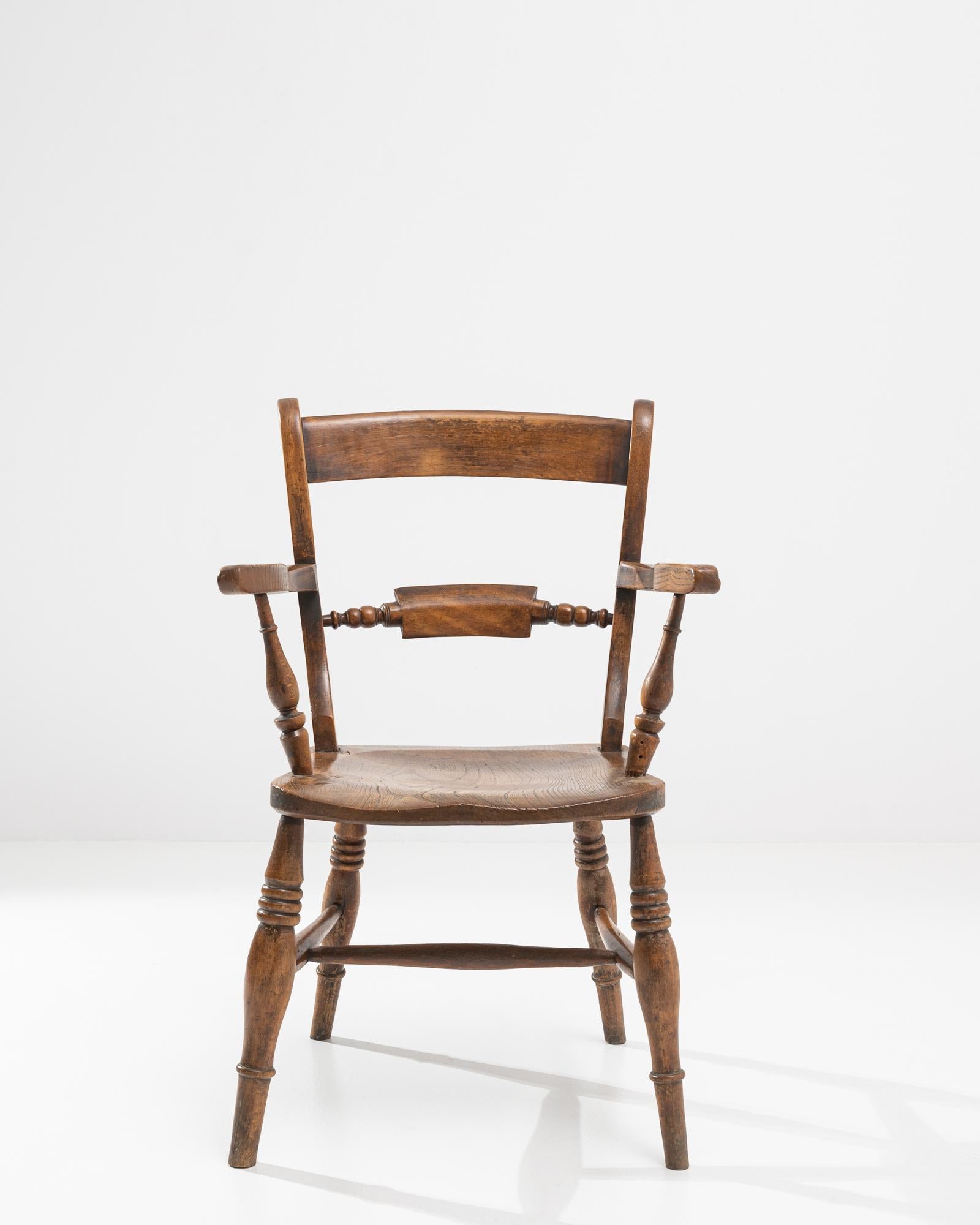 A French chair from the 19th century. This wooden chair offers a comfortable and elevated moment of rest. The carved back curves ergonomically, while sloping arm rails and square legs create a harmonious synergy throughout its construction. Its rich