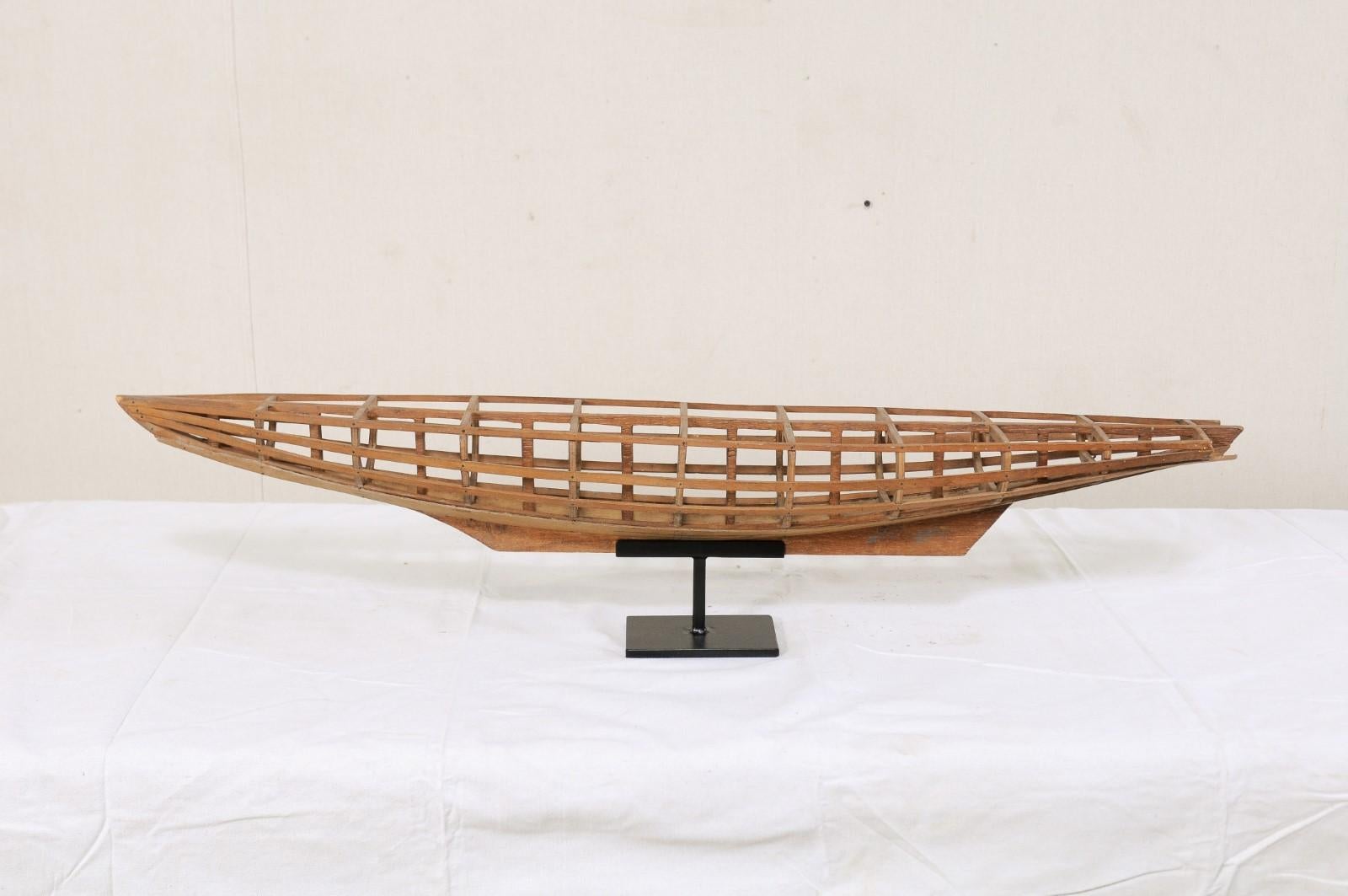 A French wooden boat model from the late 19th-early 20th century on custom stand. This antique boat model from France consists of a wooden open carcass of beams and ribs, just over 3.5 feet in length, which is nicely displayed and raised upon a