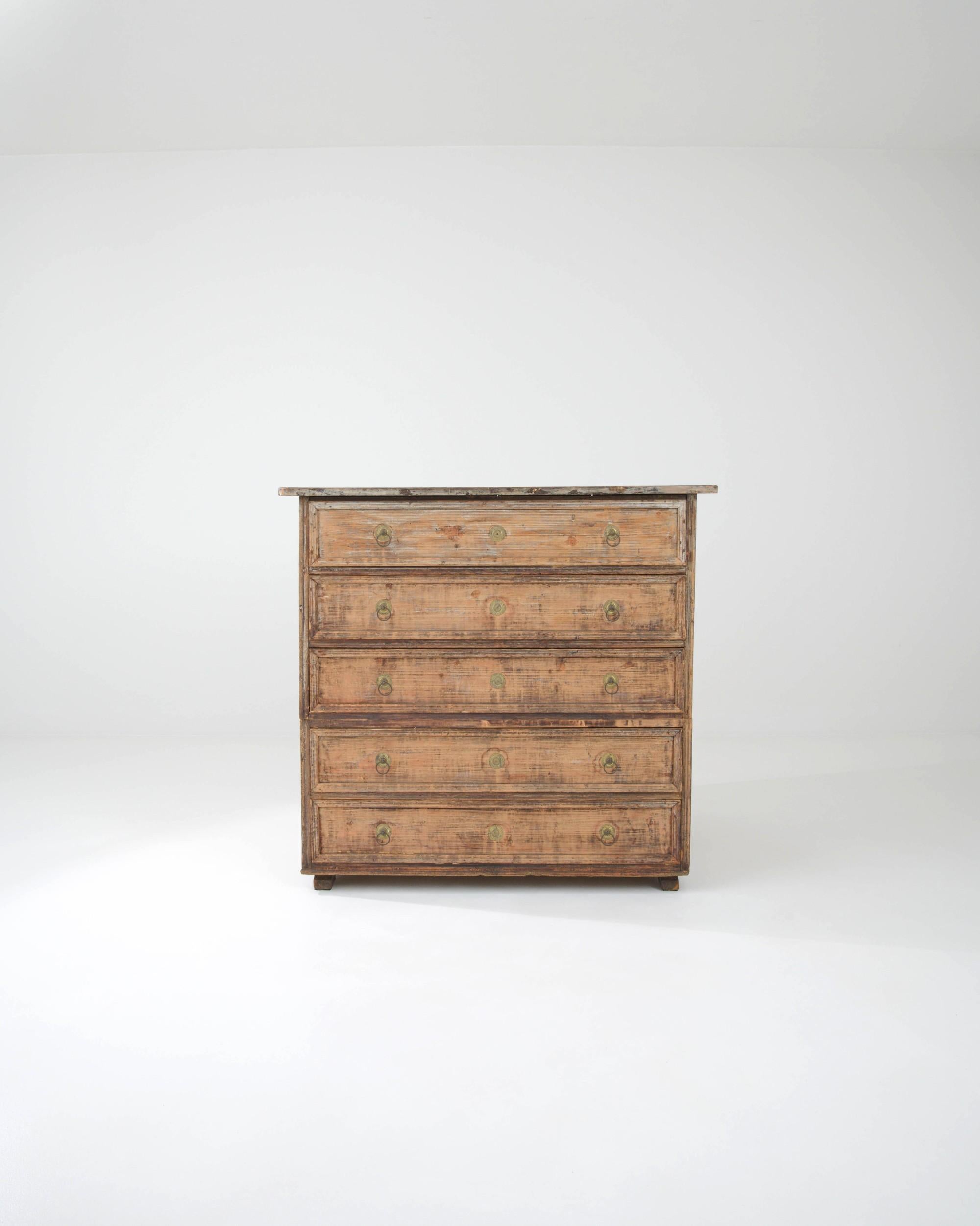 A nostalgic patina gives this antique wooden chest of drawers a romantic charm. Hand-made in France in the 1800s, the design has an elegant Neoclassical character. Simple, clean lines and discreet paneling evoke an air of refinement. The drawers are