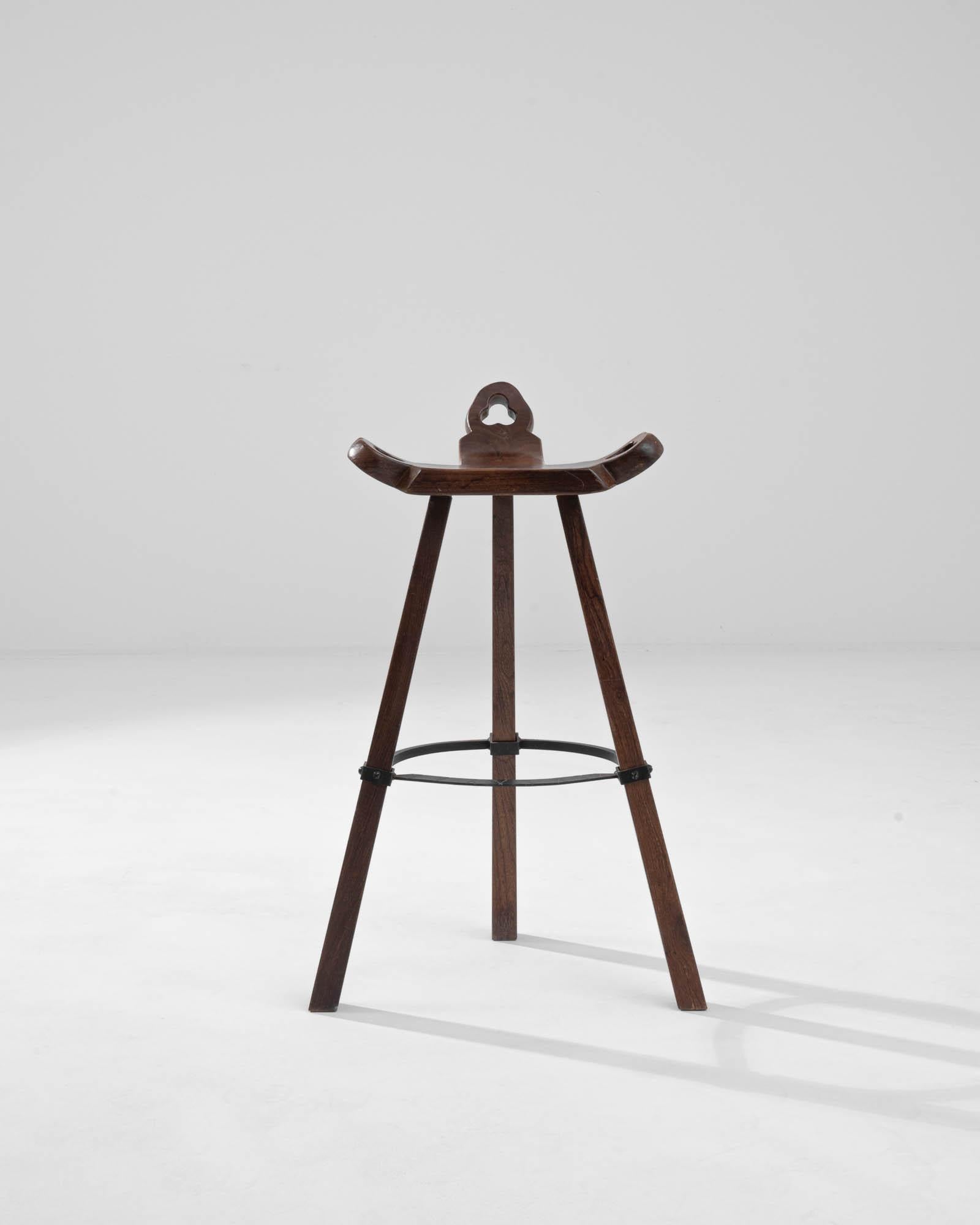 Ein Holzhocker aus dem Frankreich des 19. Jahrhunderts. Von der dreieckig geformten Sitzfläche dieses kuriosen Barhockers geht ein Dreibein aus sich sanft verjüngenden Beinen aus. Drei Schnitzereien, die drei Kreise enthalten, lassen auf rätselhafte