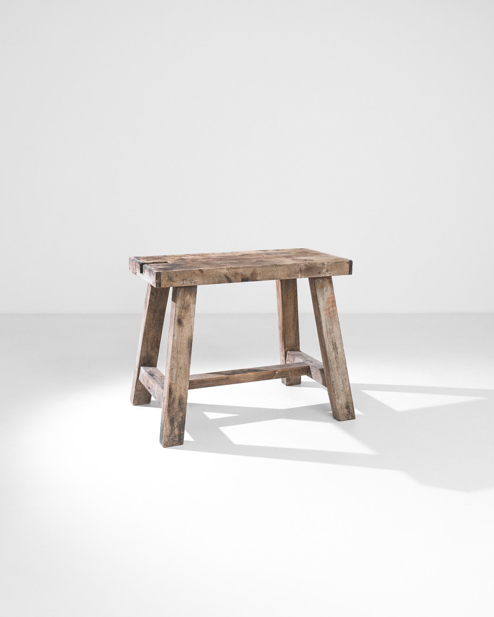 A wooden work table produced in France circa 1900. Four angled, rectangular legs connected by thick stretchers support a broad slab of working surface in its original patina. With a sturdy silhouette that shan’t be shaken by any trial or trouble,