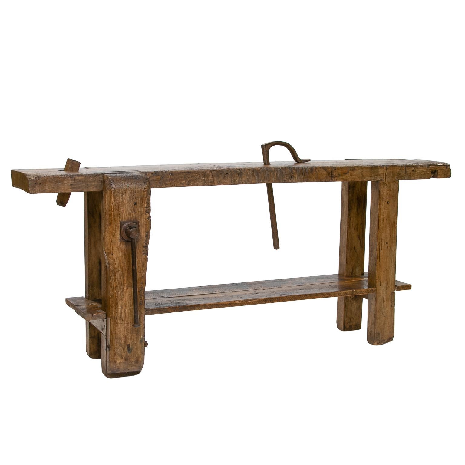 This antique French workbench is made of beechwood with a vice, a studded claw, and an iron clamp. This piece also has a lower shelf and all parts are fully functional. The size of this piece is great for use as a narrow console.