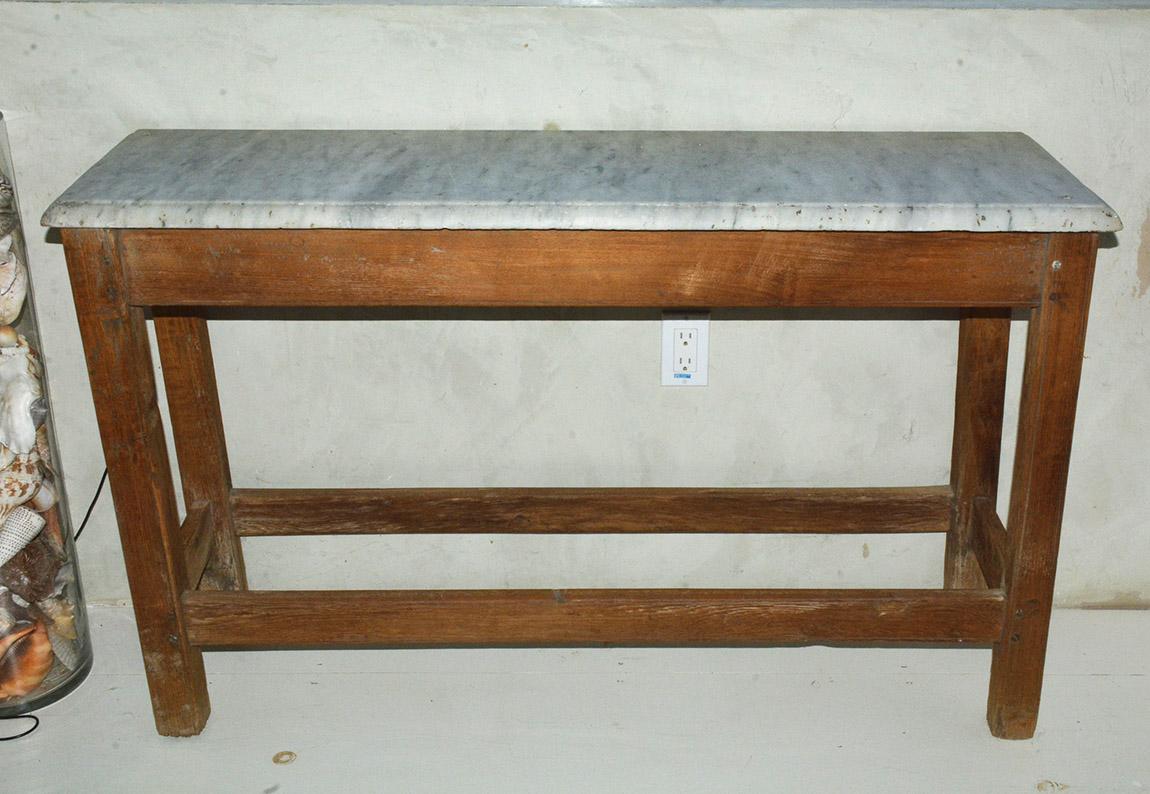 The wonderfully sturdy rustic French country Provincial style worktable or serving console table is constructed of slotted framing to hold a veined marble top having beveled edges with wonderful aged patina and lots of character. Can be used as