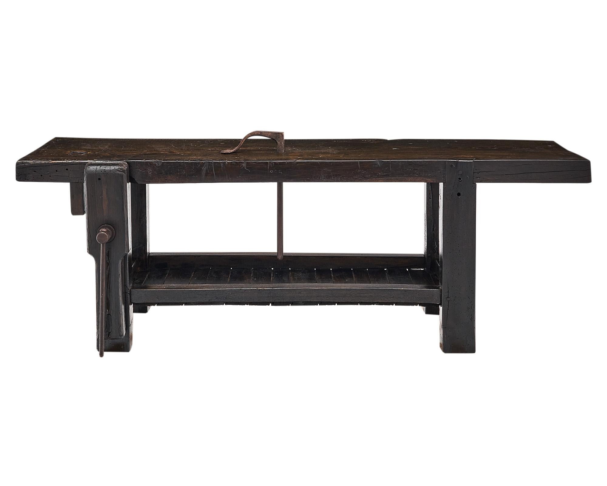 Workbench from the French Alps made of waxed and patinated chestnut wood. The bench features the original vise and clamp of forged iron as well as a bottom planked shelf. The depth listed is for the full depth including the vise, the depth of the