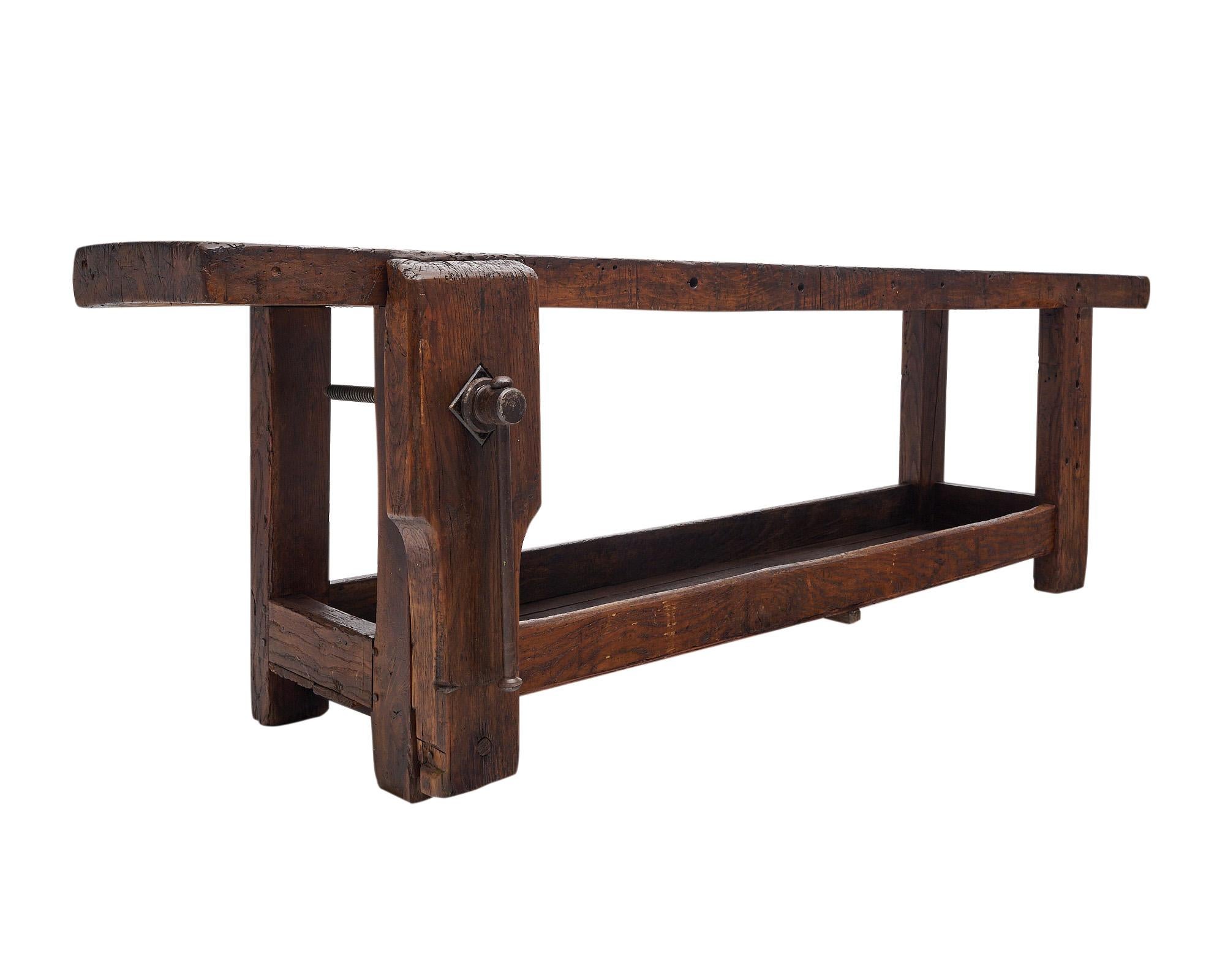 Workbench from the French Alps made of waxed and patinated chestnut wood. The bench features the original vise and clamp of forged iron as well as a bottom planked shelf. Originally used for crafting skis, this is a striking piece with a lot of