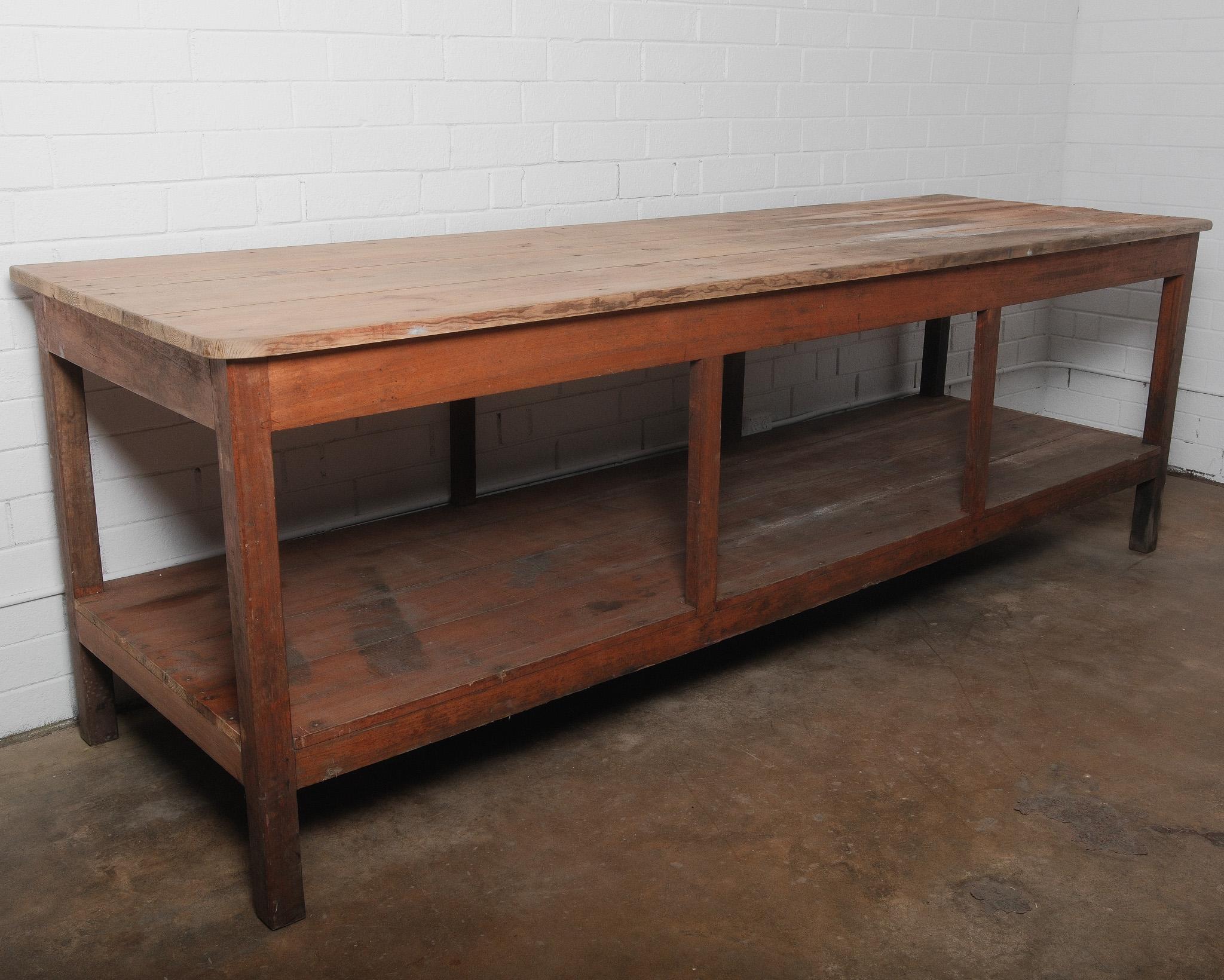 This large antique French workbench table is a true statement piece, blending form and function with its timeworn character and solid craftsmanship. The thick plank tabletop tells a story of decades of use, showcasing a naturally distressed surface