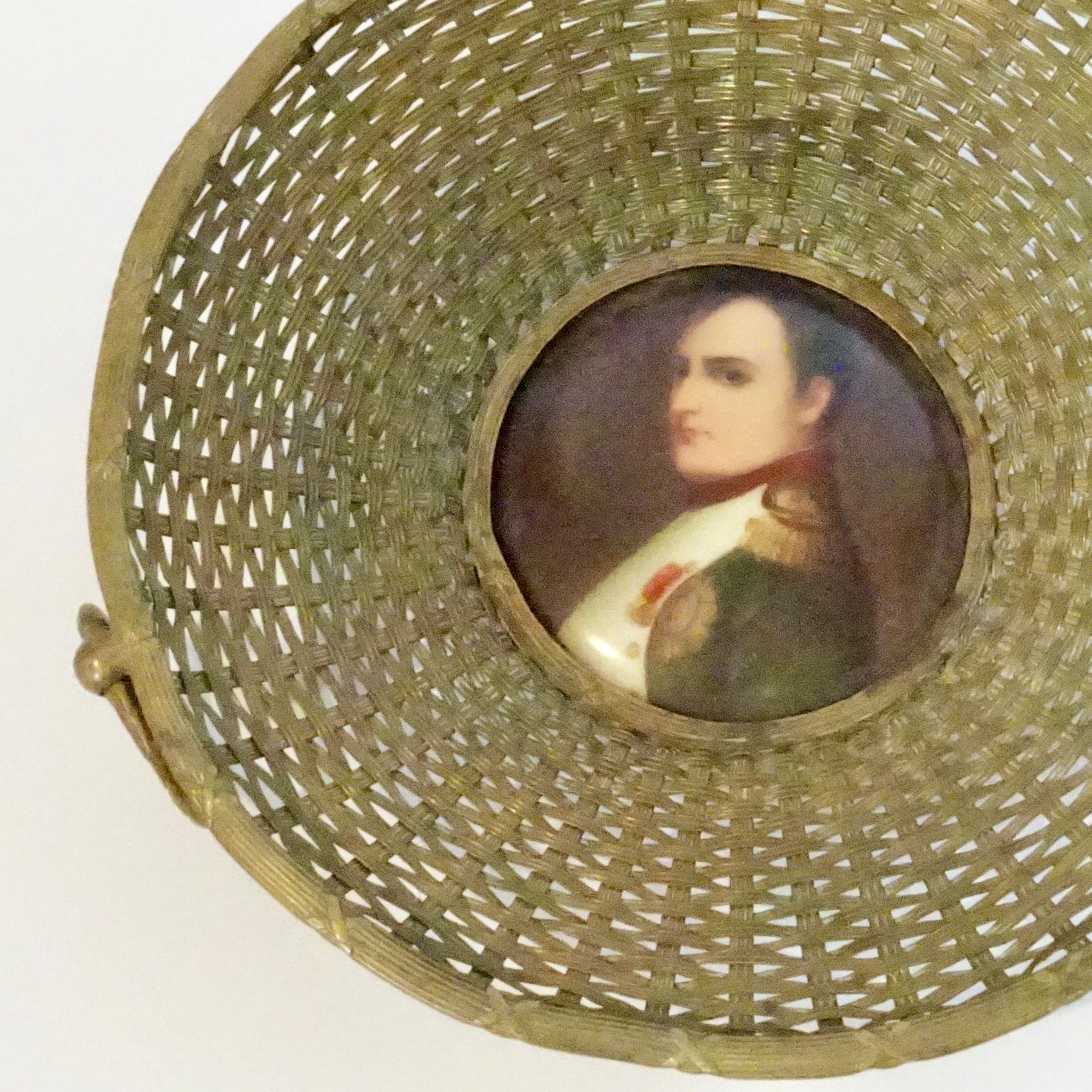 This is a stunning 19th century French woven basket with three circular handles. There is a beautifully detailed painting of Napoleon displayed in the center.