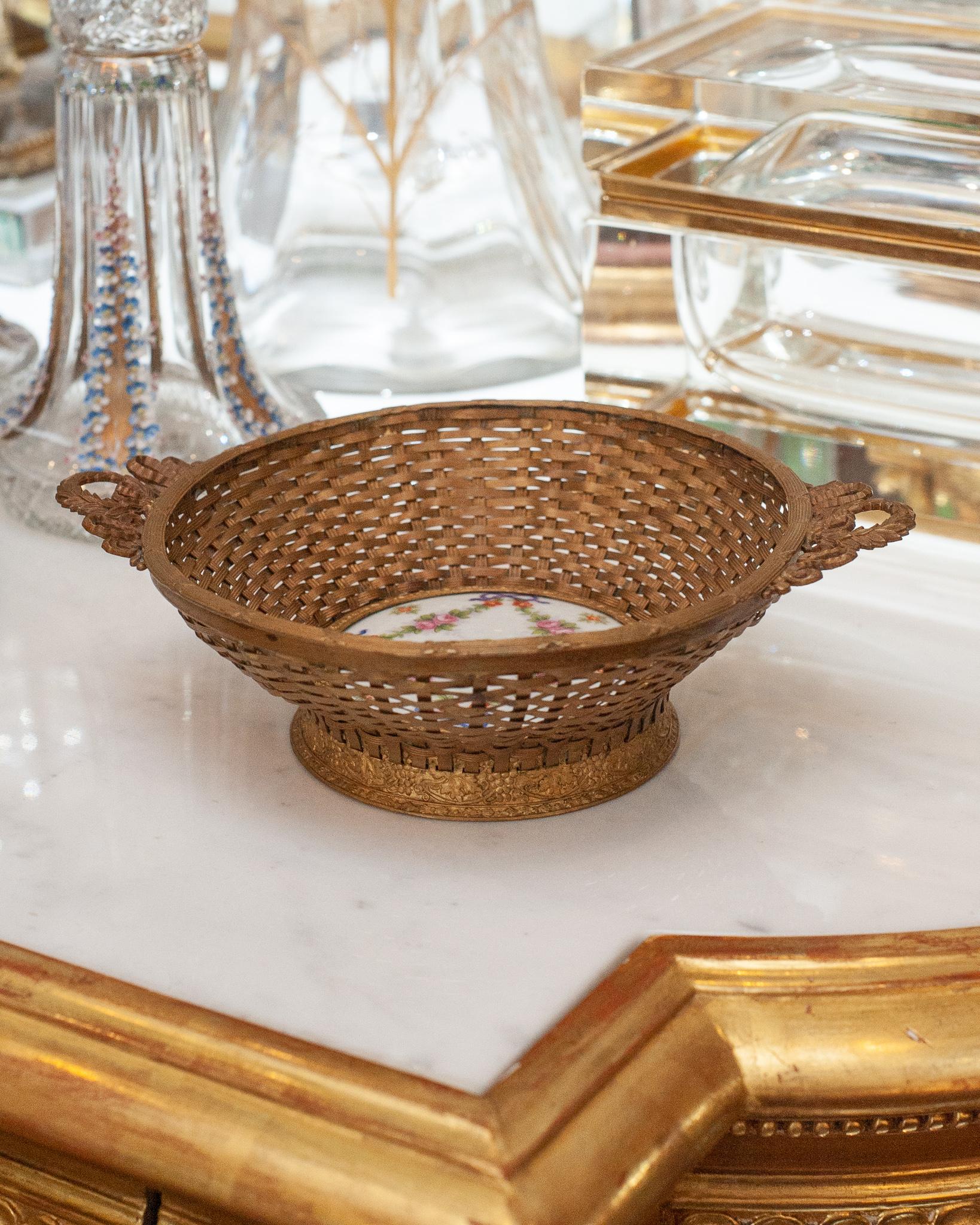 Un superbe panier ancien en bronze tressé français avec une plaque centrale en porcelaine imprimée à la main. Magnifiquement et délicatement construit, ce panier est un complément parfait à toute table.
