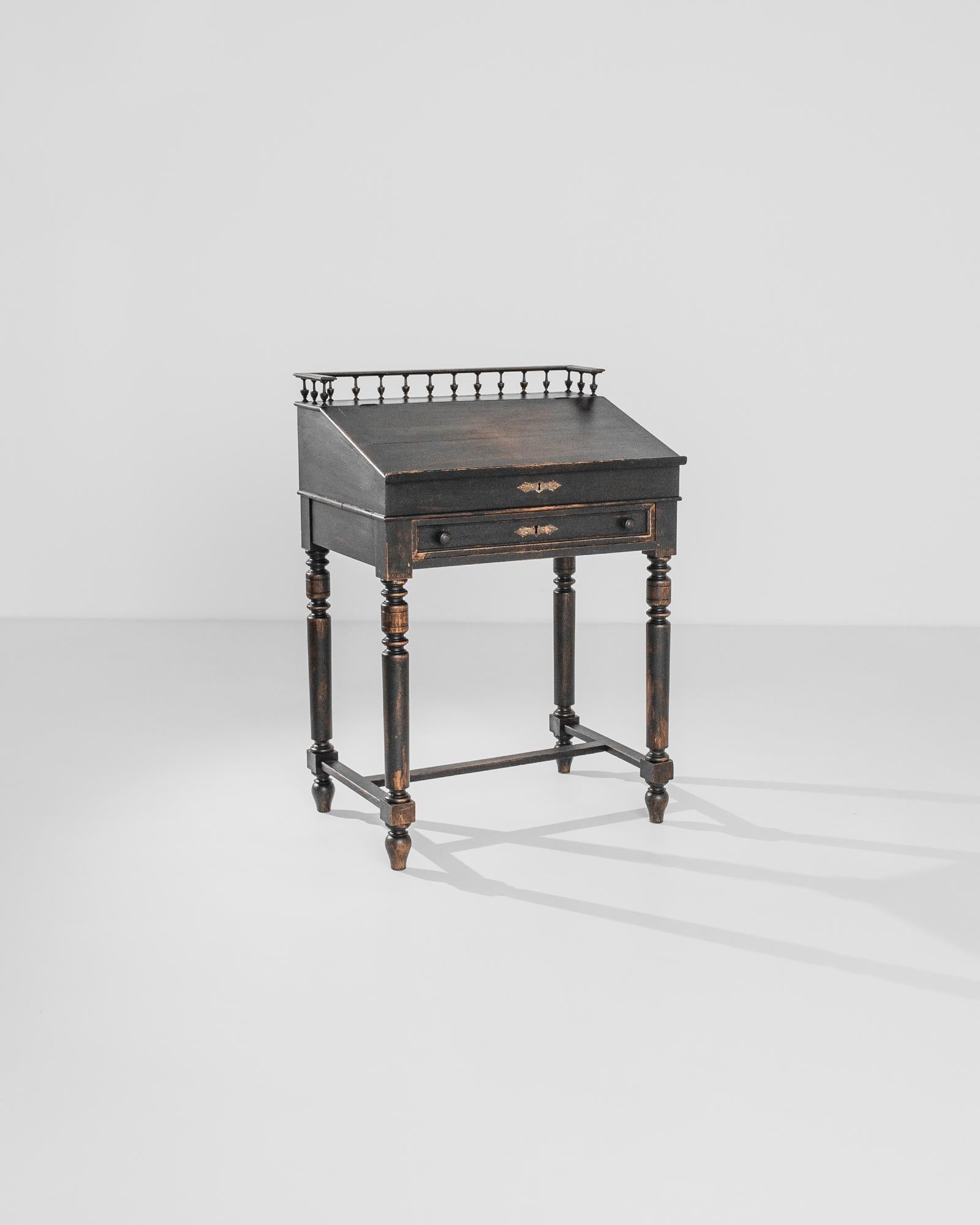 A petite black writing table made in France circa 1890. Like a majestic concert piano, this deluxe black desk has a hinged top that reveals two secret drawers with intriguing handwritten notes on them. The external drawer is decorated with iron