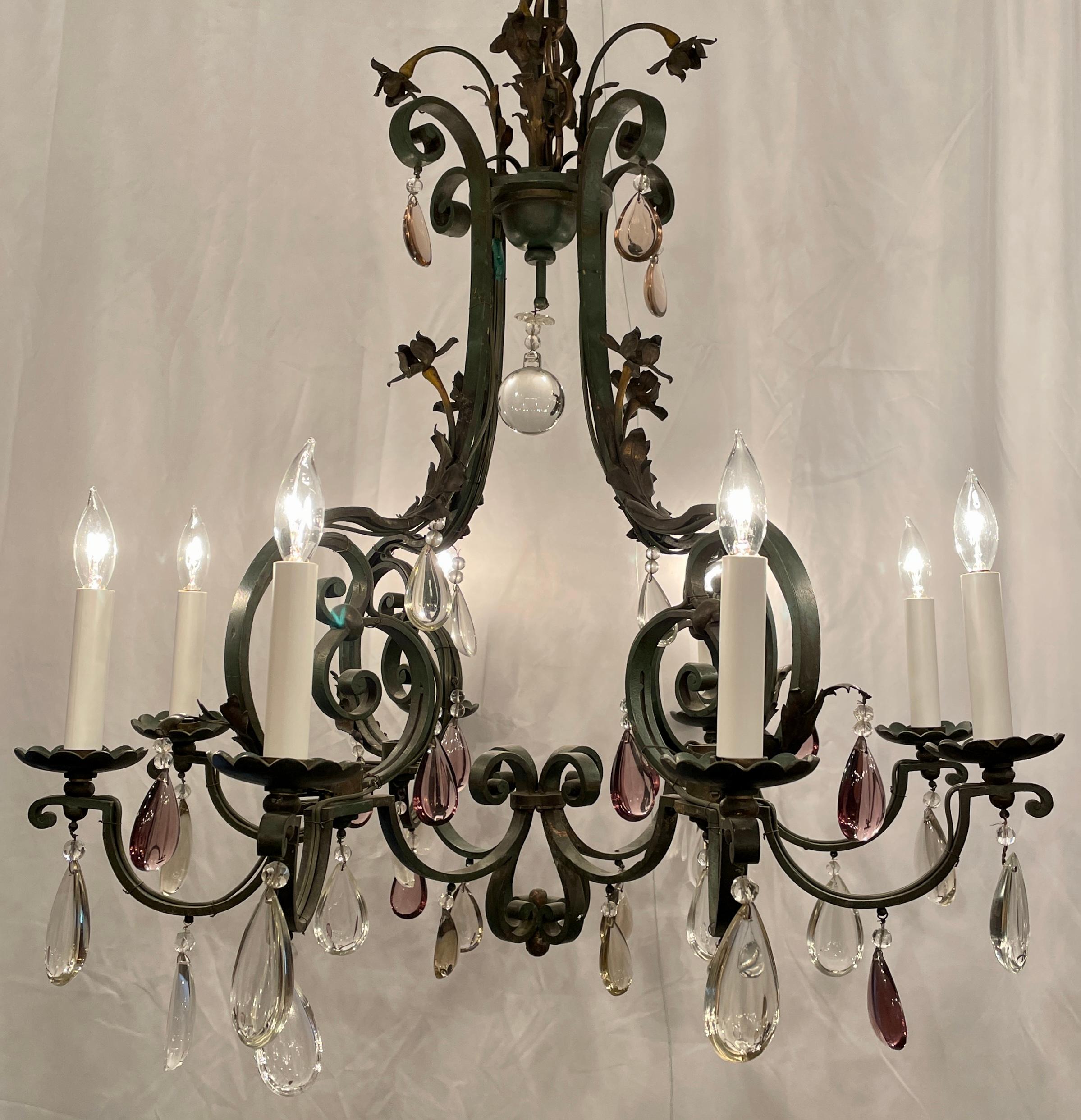 Lustre antique français en fer forgé et cristal à 8 lumières, Circa 1920.
Magnifique lustre en fer forgé à la main avec des prismes polis clairs et violets.