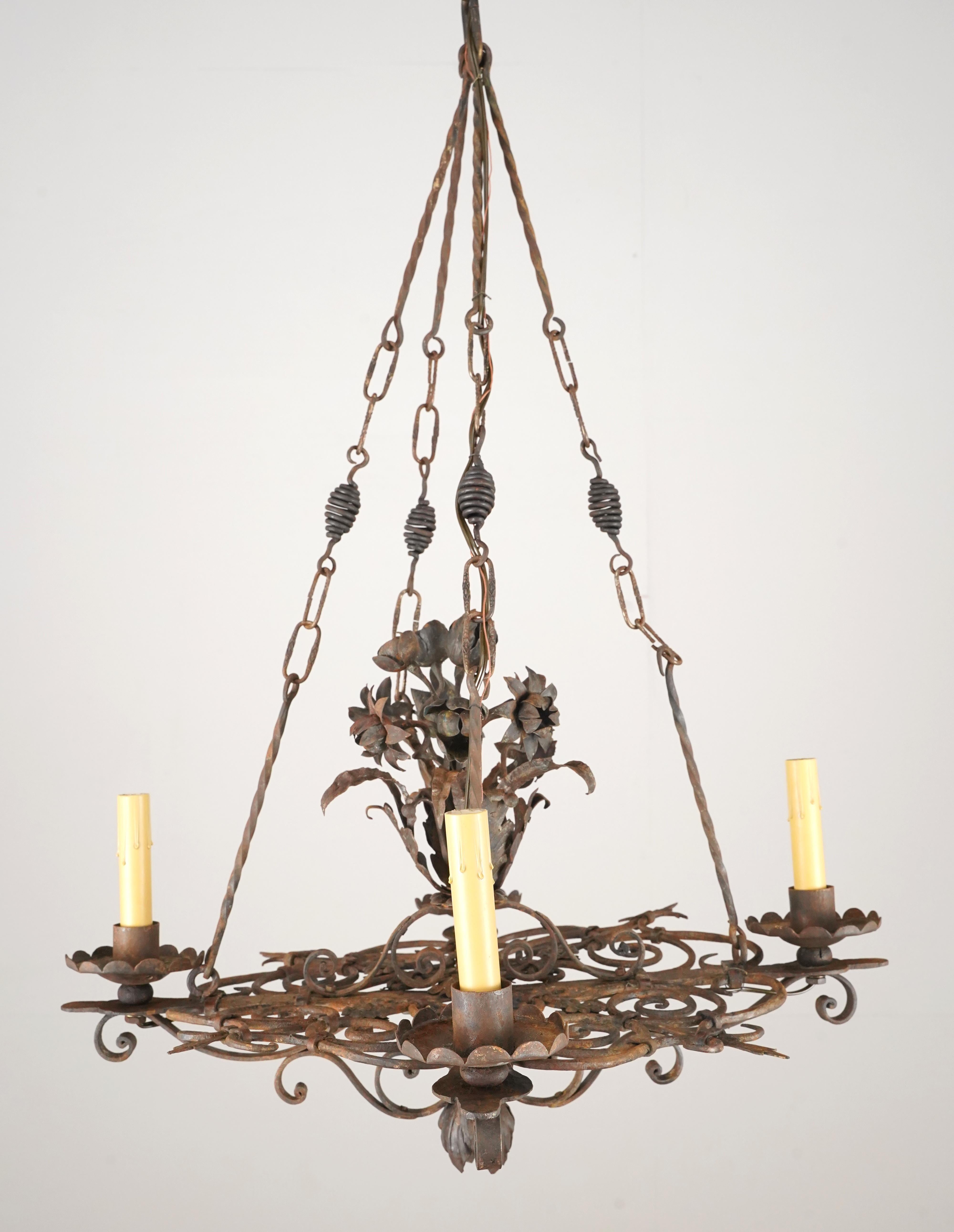 Araña de estilo Antique French de hierro forjado con cuatro brazos. La cadena y el tejadillo son de acero. Cada candelabro requiere cuatro bombillas candelabro E-12. Esta luz está limpia y restaurada. Buen estado con desgaste superficial y óxido.