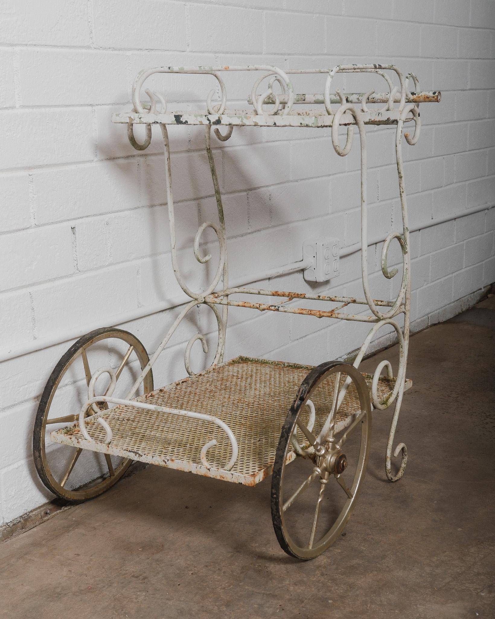 Cet élégant chariot de bar français ancien est un bel exemple de l'artisanat du fer forgé du début du XXe siècle. Cette pièce est à la fois décorative et fonctionnelle. Elle comporte des volutes complexes, de grandes roues à rayons avec des jantes