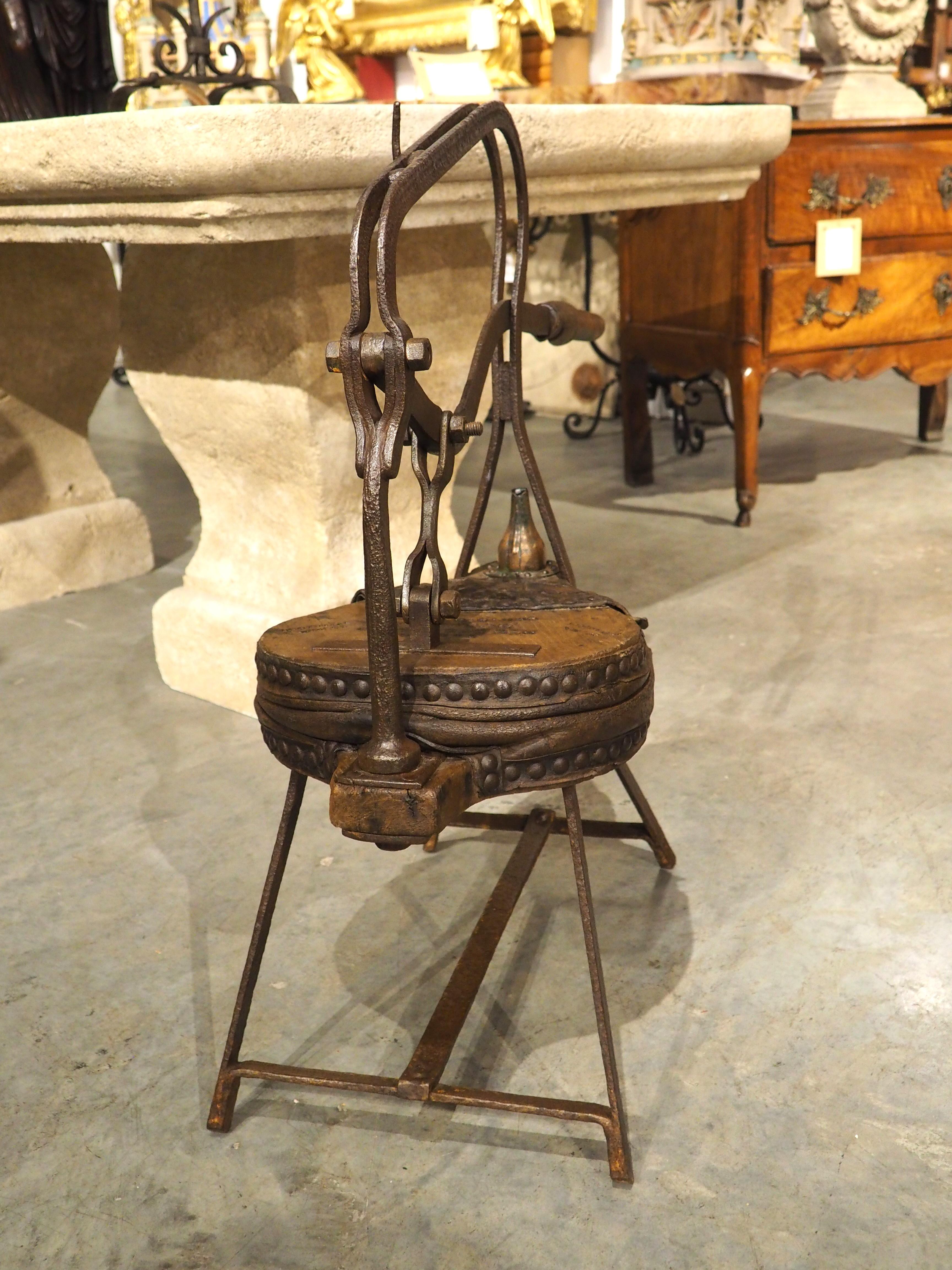 Dieser schmiedeeiserne Blasebalg, ein faszinierendes Instrument aus dem 19. Jahrhundert, das in Frankreich als soufflet de barrique bekannt ist, wurde einst auf einem Weingut in Bordeaux verwendet. Der hölzerne Blasebalg ist mit gegerbtem Leder