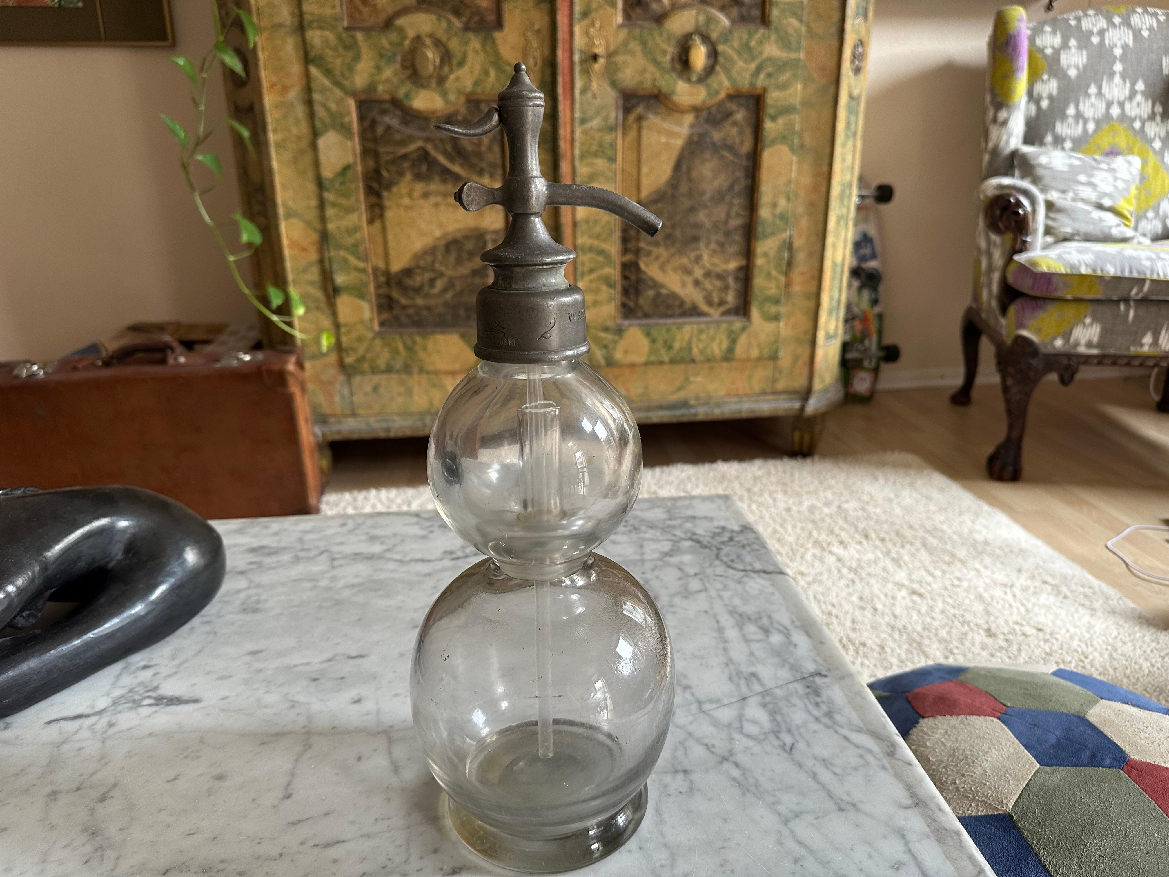 This antique French soda siphon dates back to around 1890 and originates from Paris, making it a rare and authentic piece of 19th-century barware. The siphon stands out with its unusual double-bulb design, a feature that makes it highly collectible