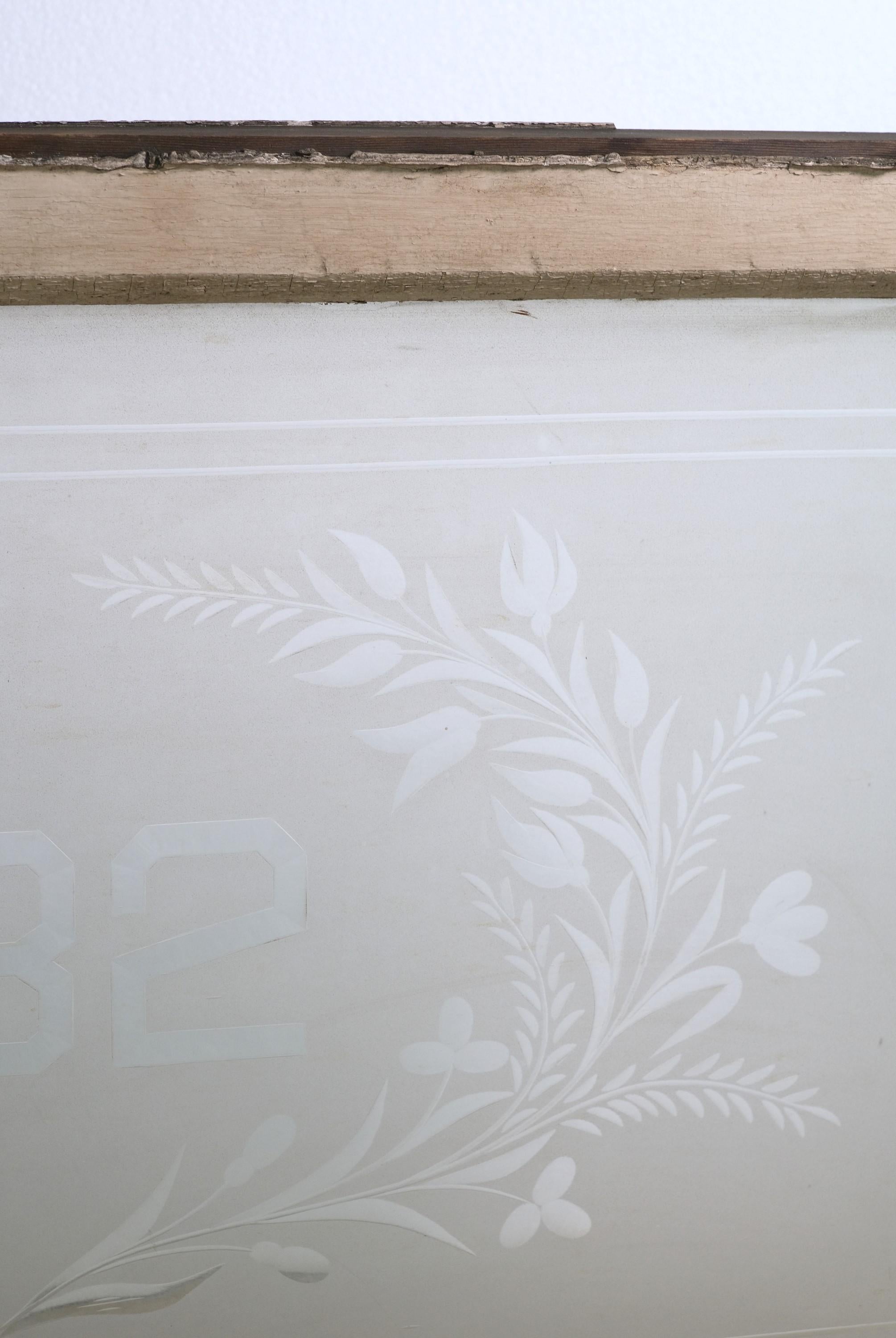 Antique frosted glass window transom with etched foliate details and house number 332 in the center. It has a pine frame which is painted an off white on one side and a brighter white on the opposite side. The glass is in very good condition, while