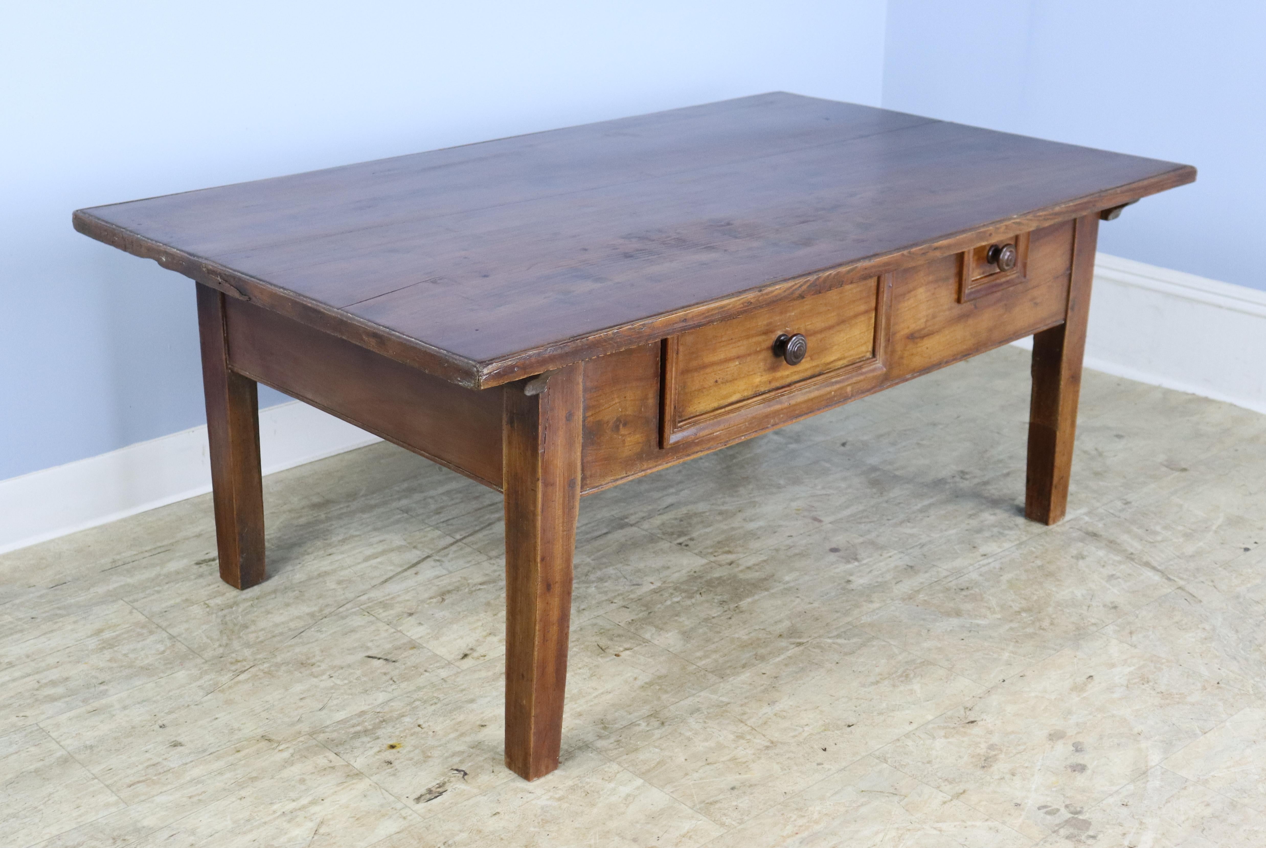 A beautifully grained Alsacian coffee table in mellow fruitwood. The top has wonderful color and patina, while the look of the front is punctuated by two sweet drawers. Chunky stylized legs complete the look.