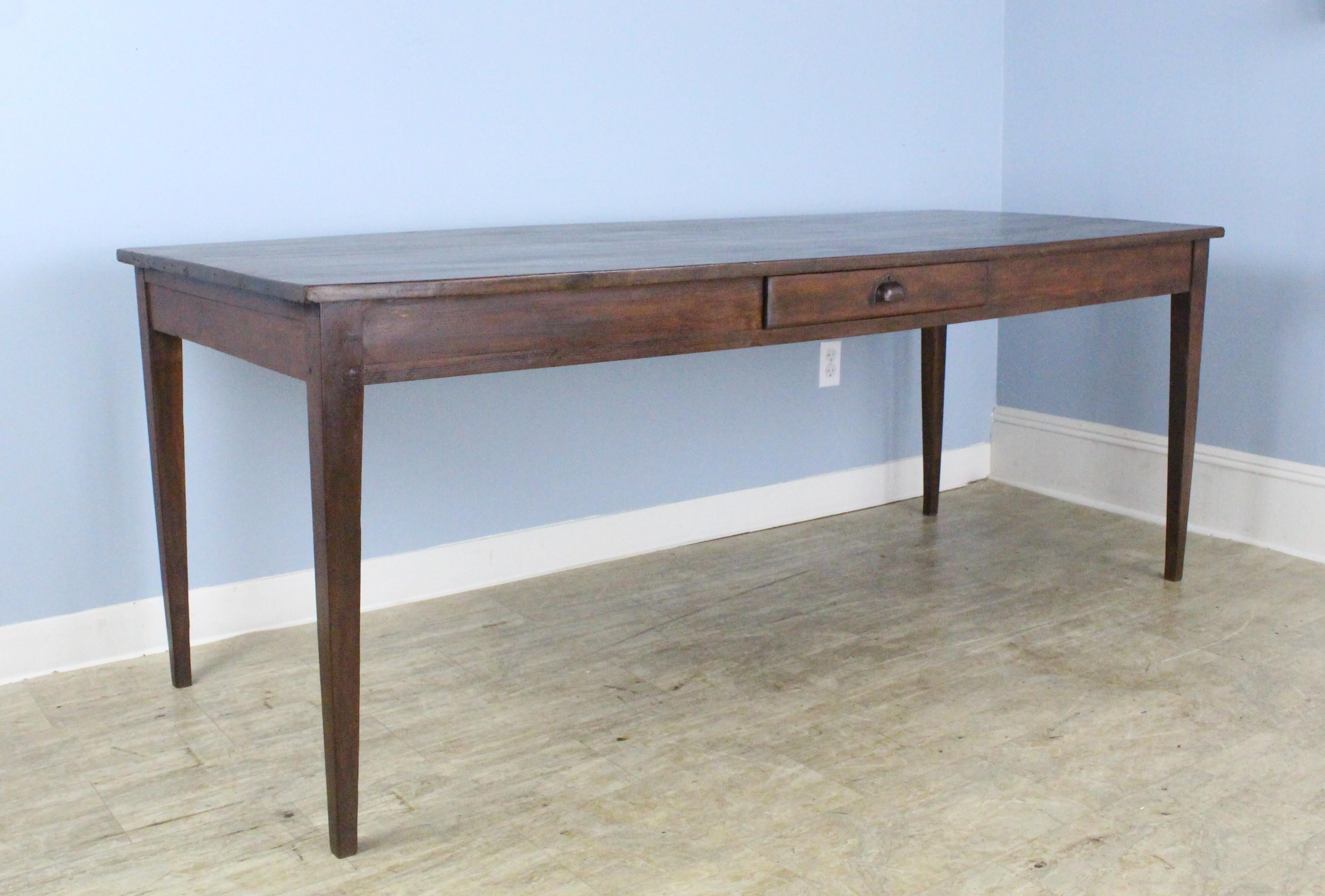 This handsome mid-brown fruitwood farm table is sturdy and elegant. Slender tapered legs and good grain. There is a useful drawer on one side. The apron height is a good 25