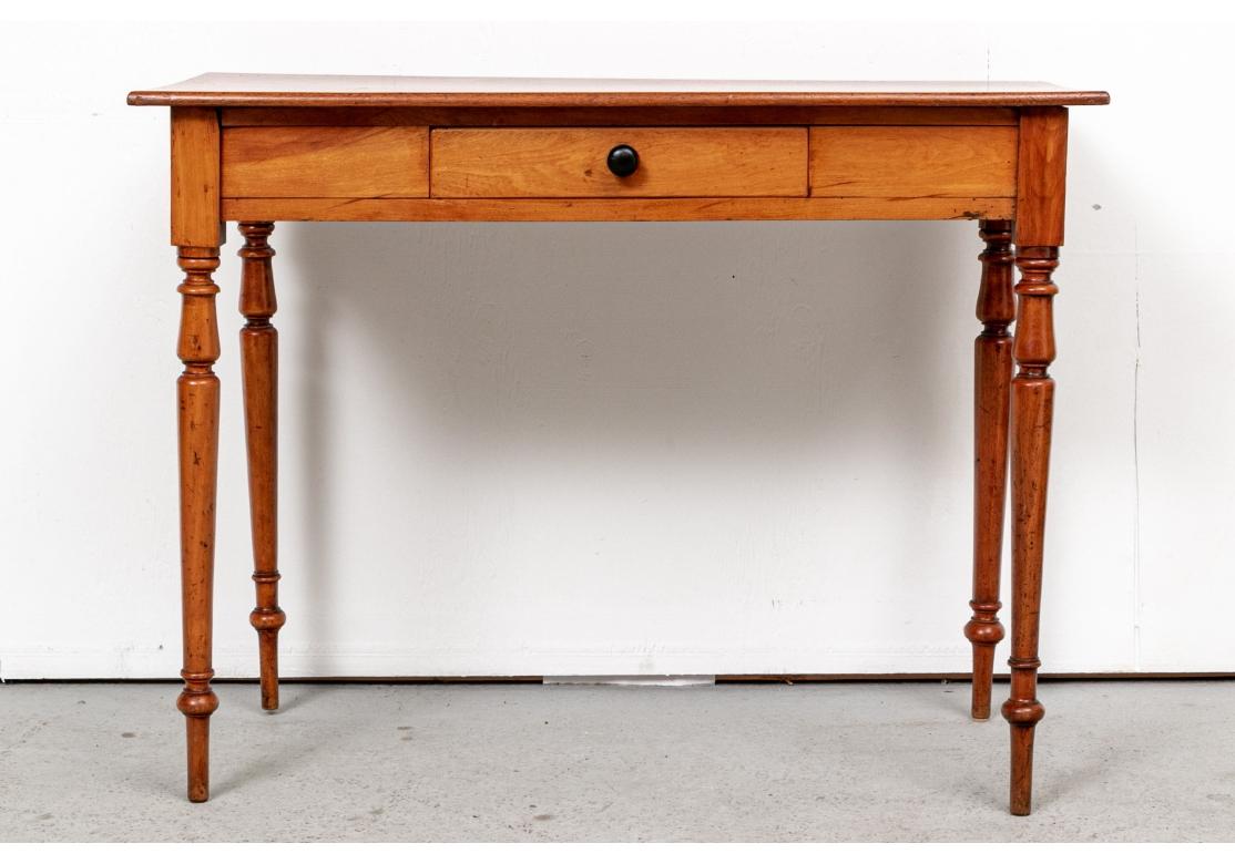 A refined Antique Country table in colorful wood suitable as a writing table or Hall Table. With classic lines and overhanging top. A small center apron drawer with darker wood knob pull. Raised on elegant tall turned legs with peg feet. 

L. 38